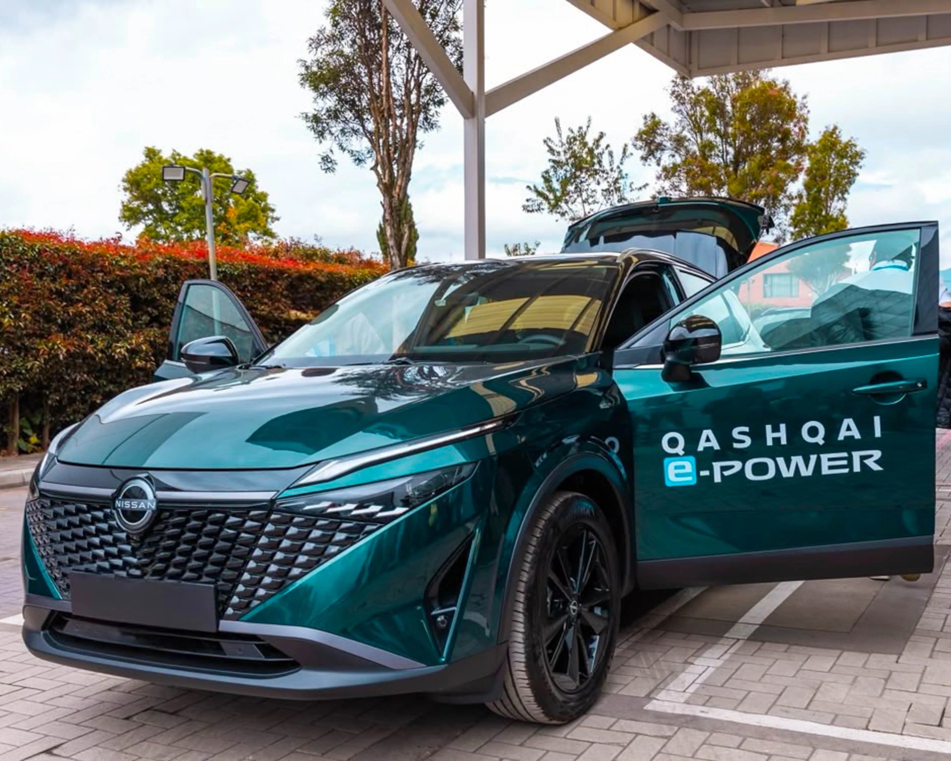 Teal Nissan Qashqai e-Power SUV with front and rear doors open, parked under a canopy.