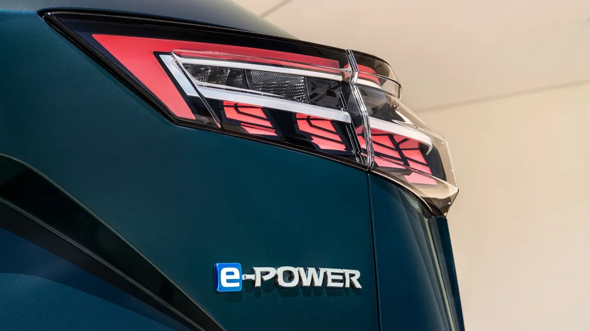 Close-up of a dark green car's rear with a red and white taillight and a blue and silver "e-POWER" badge.