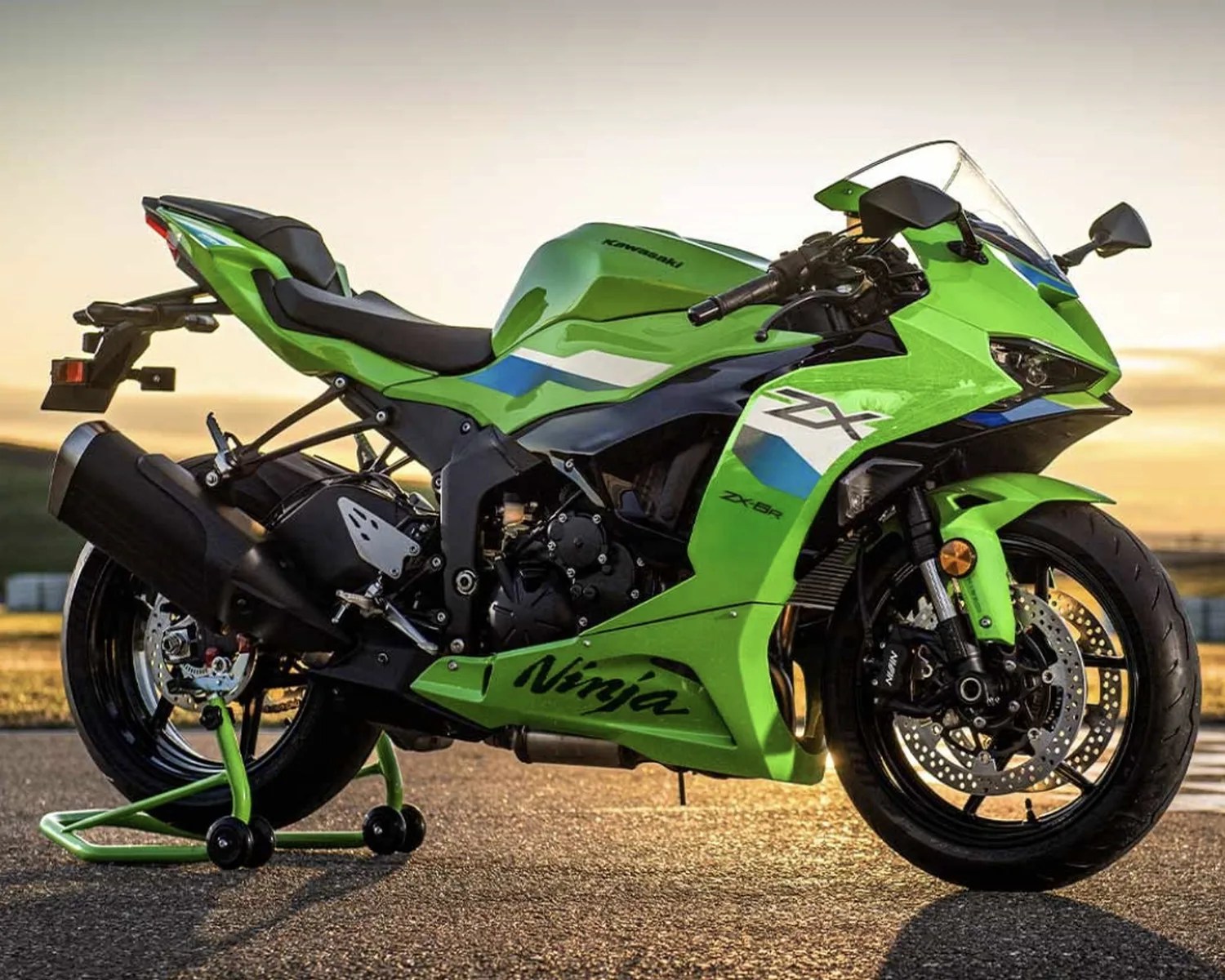 Green Kawasaki Ninja ZX-6R sport motorcycle on a rear stand at sunset.