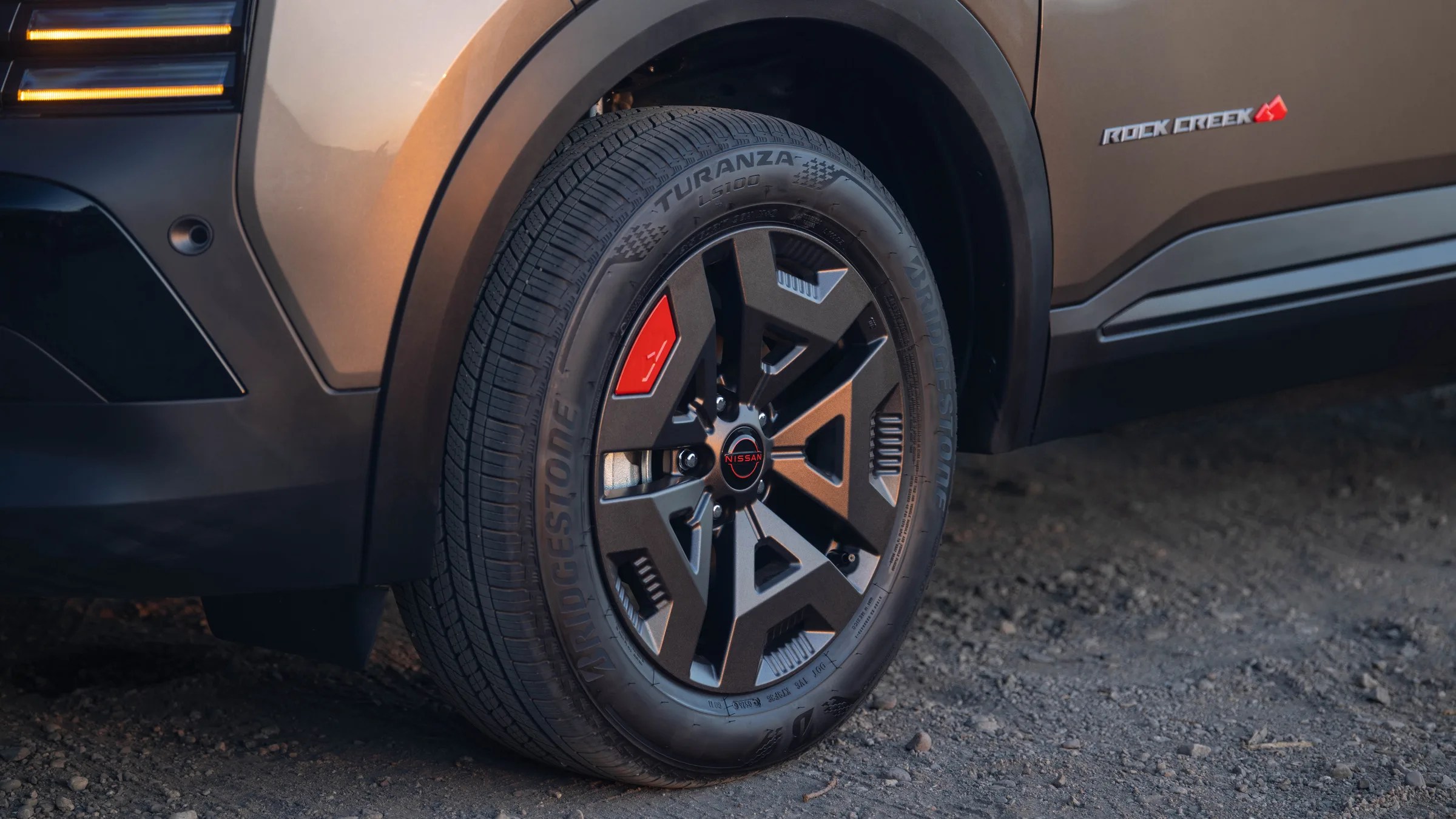 Close-up of a Bridgestone Turanza tire on a Nissan vehicle with a Rock Creek badge on the side.
