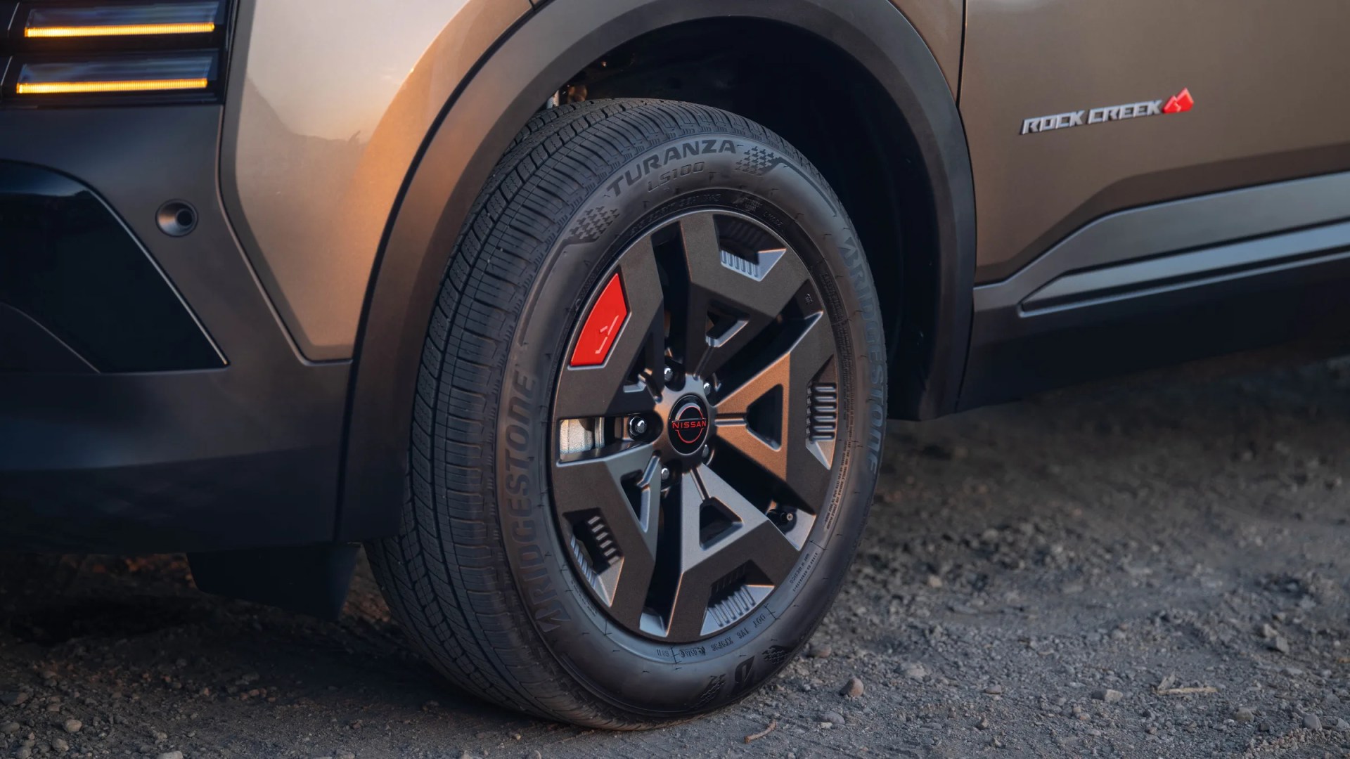 Close-up of a Bridgestone Turanza tire on a Nissan vehicle with a Rock Creek badge on the side.