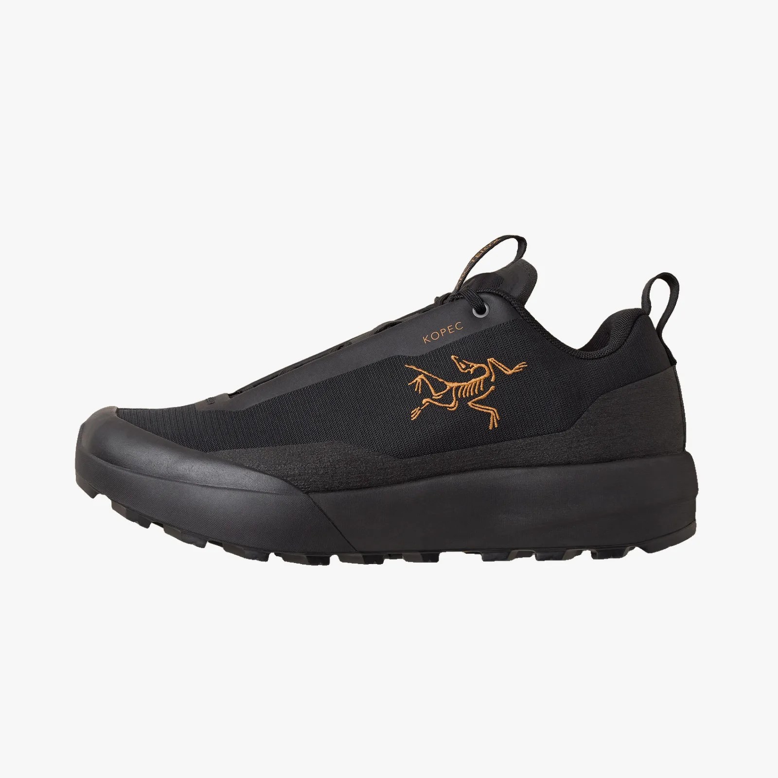 Black low-top sneaker with orange skeletal animal logo and "KOPEC" text on the side.