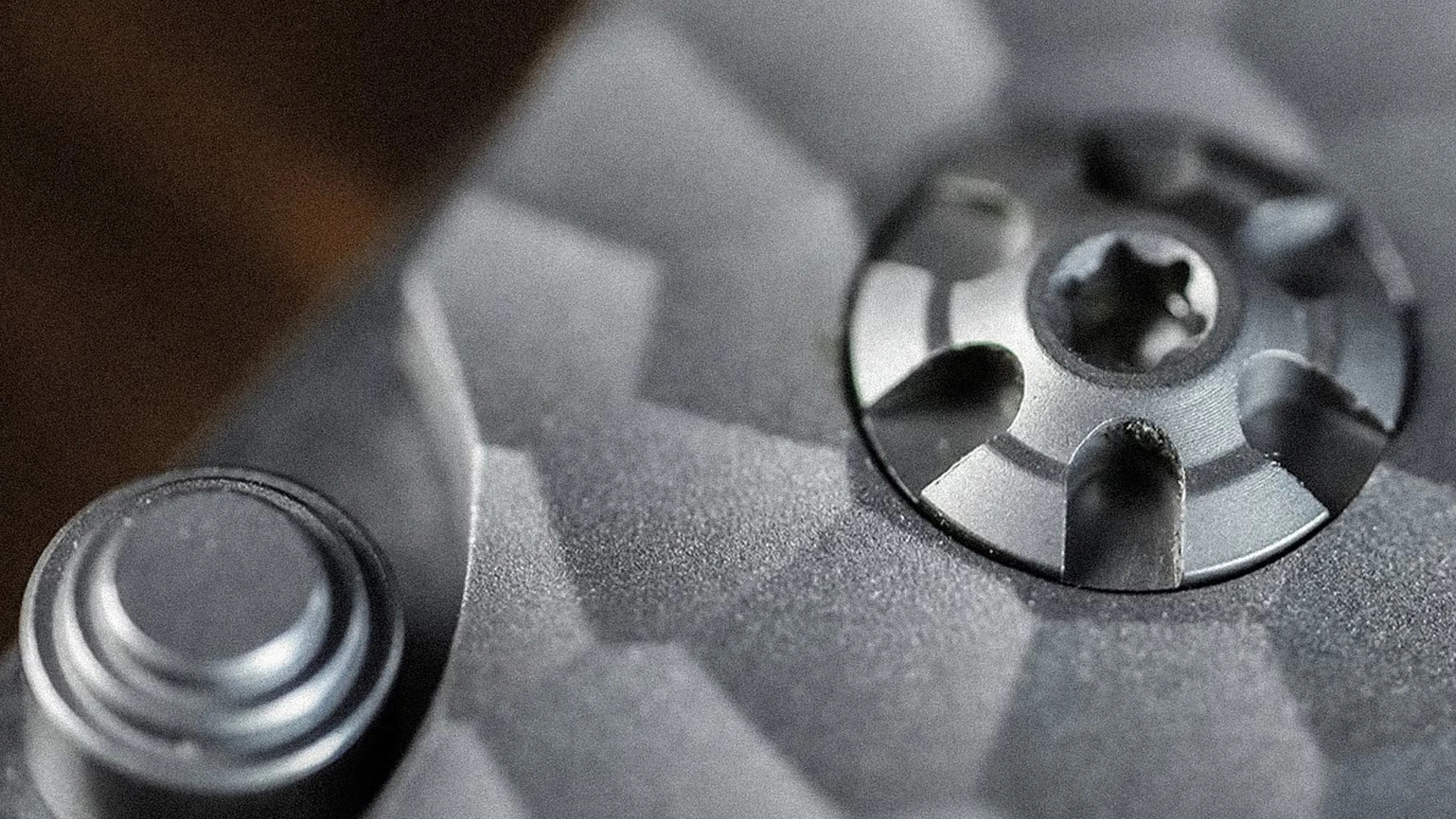 Close-up of a textured gray metal surface with a circular screw and a round button.