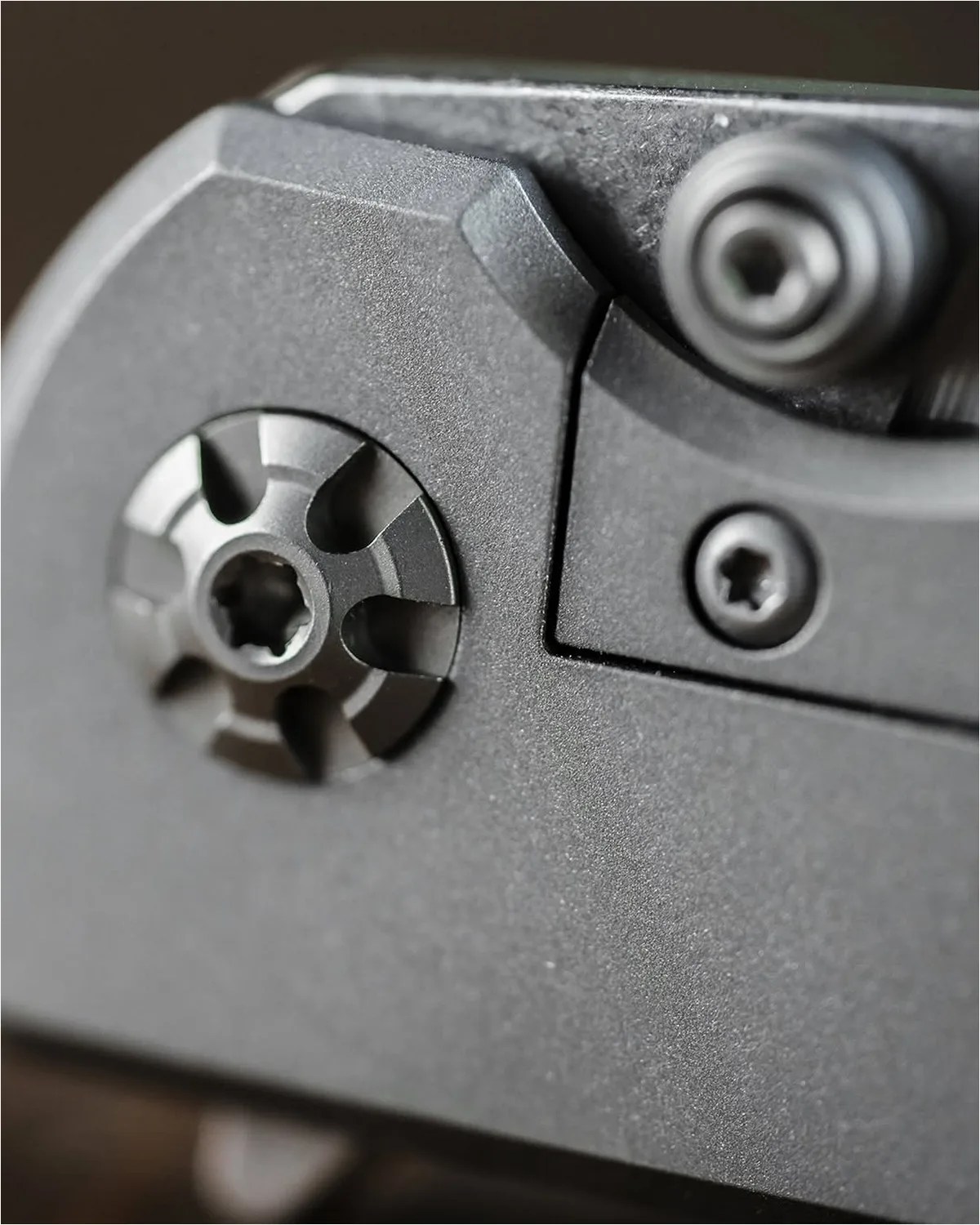 Close-up of a matte black metal device with three visible star-shaped screws.