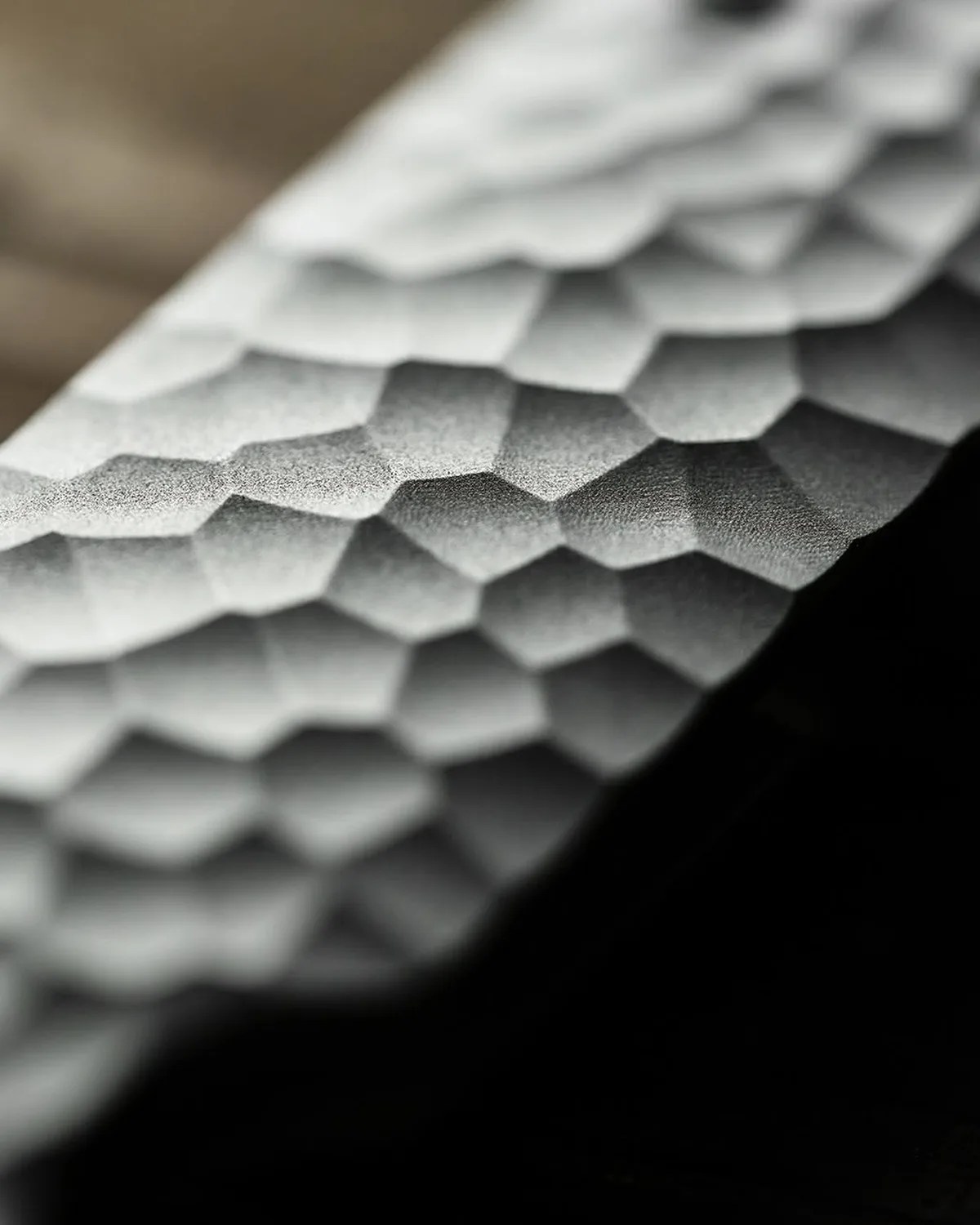 Close-up of a textured, hammered metal surface with a matte finish in grayscale.