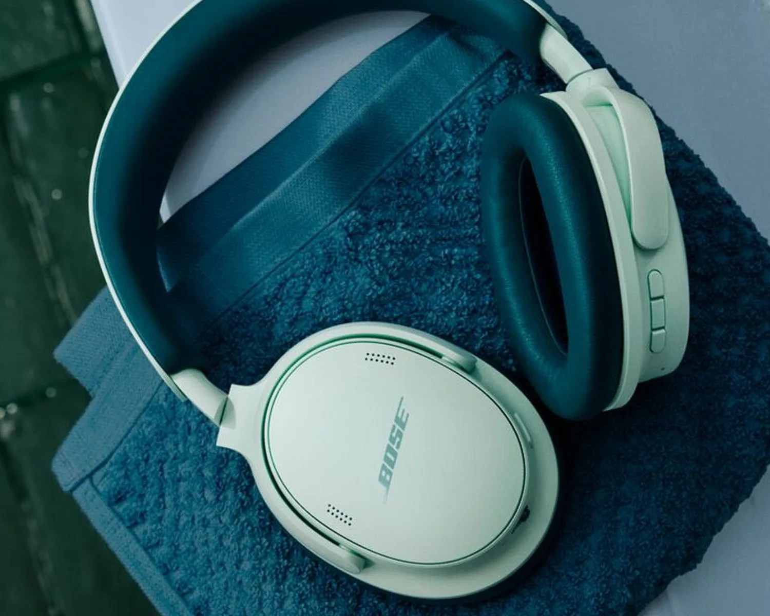 White Bose over-ear headphones with dark blue ear cushions resting on a dark blue textured fabric.