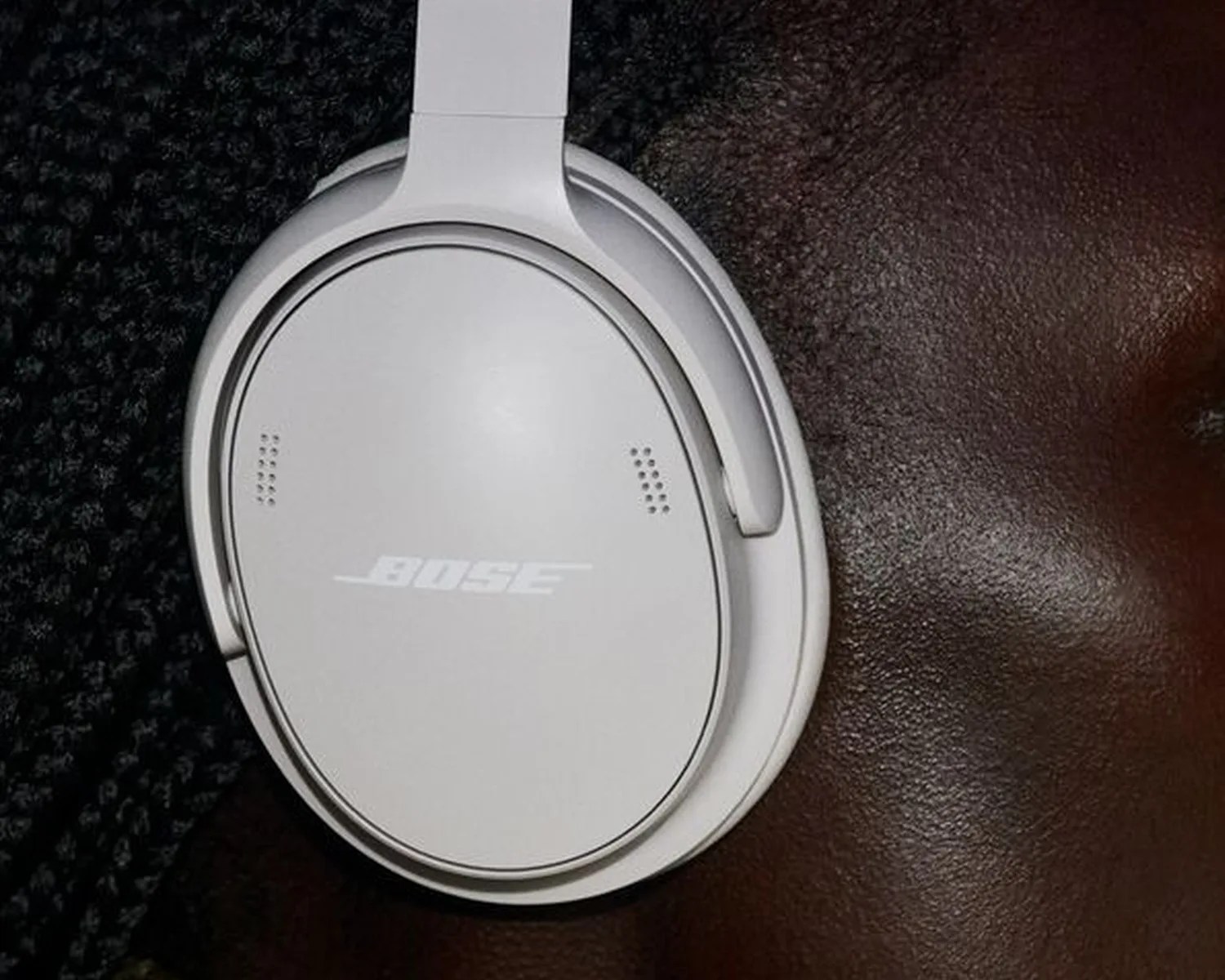 White Bose over-ear headphone earcup resting on a dark textured surface.