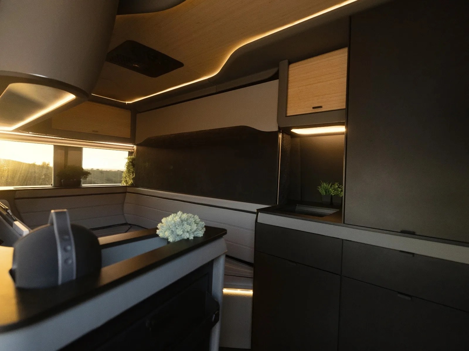 Interior of a modern camper van with black and wood cabinets, gray seating, and soft LED ceiling lighting.
