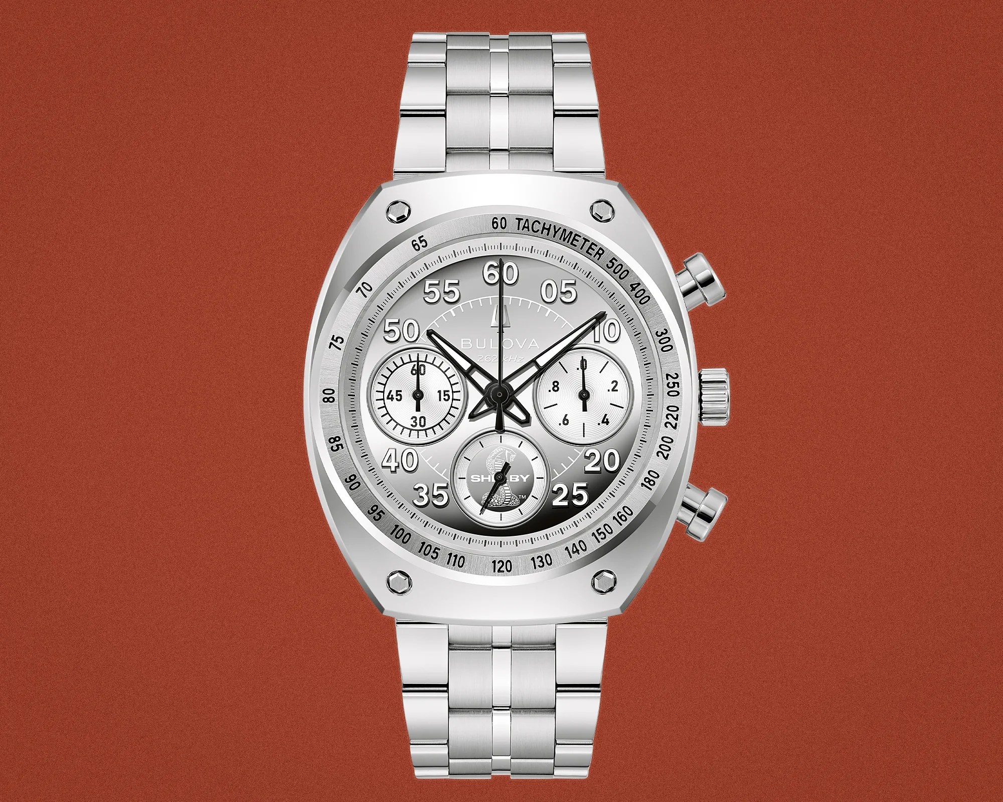 Silver Bulova chronograph watch with tachymeter bezel and metal link bracelet on a rust-colored background.
