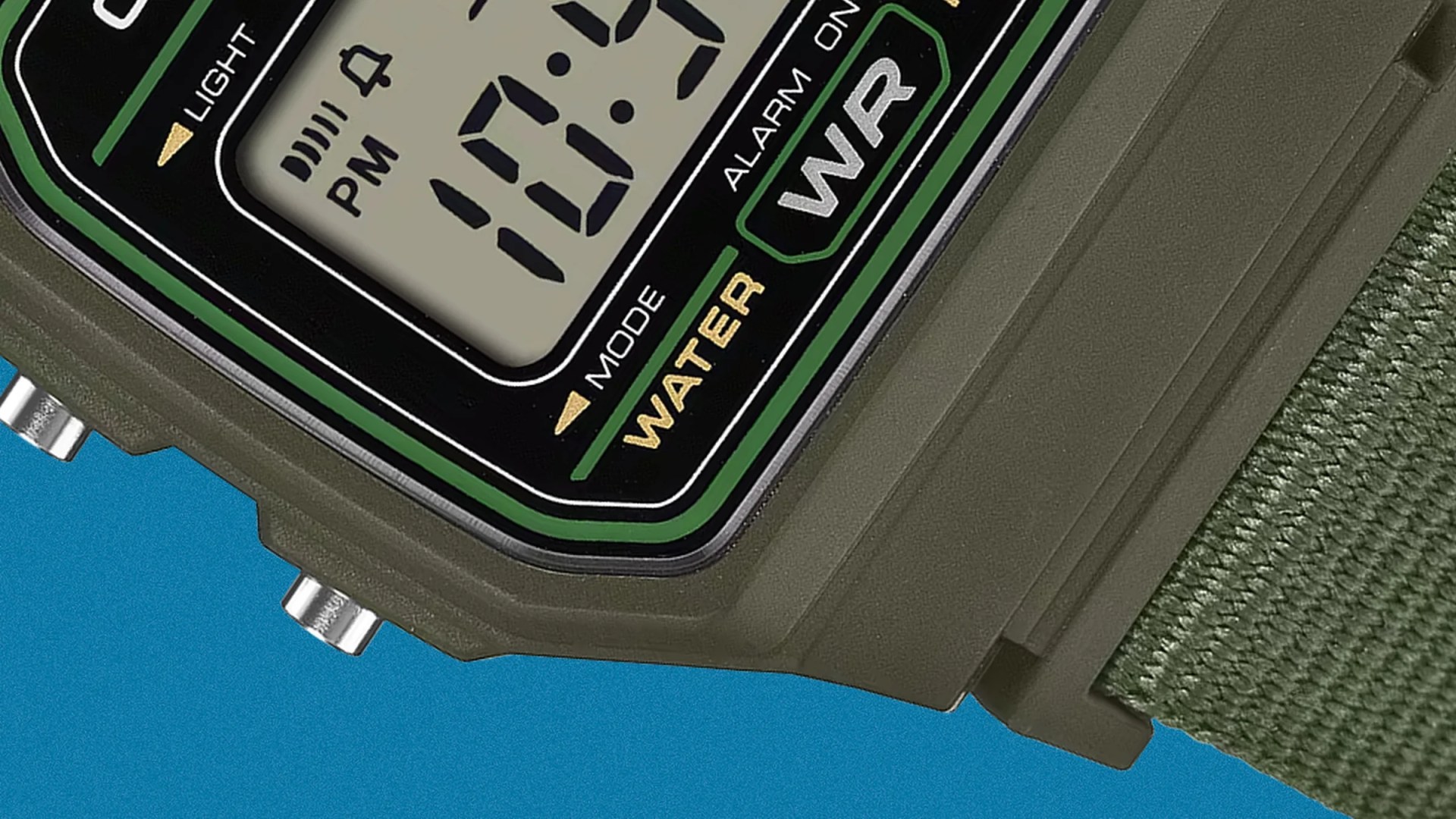 Close-up of a green digital wristwatch face showing time and mode with a green fabric strap.