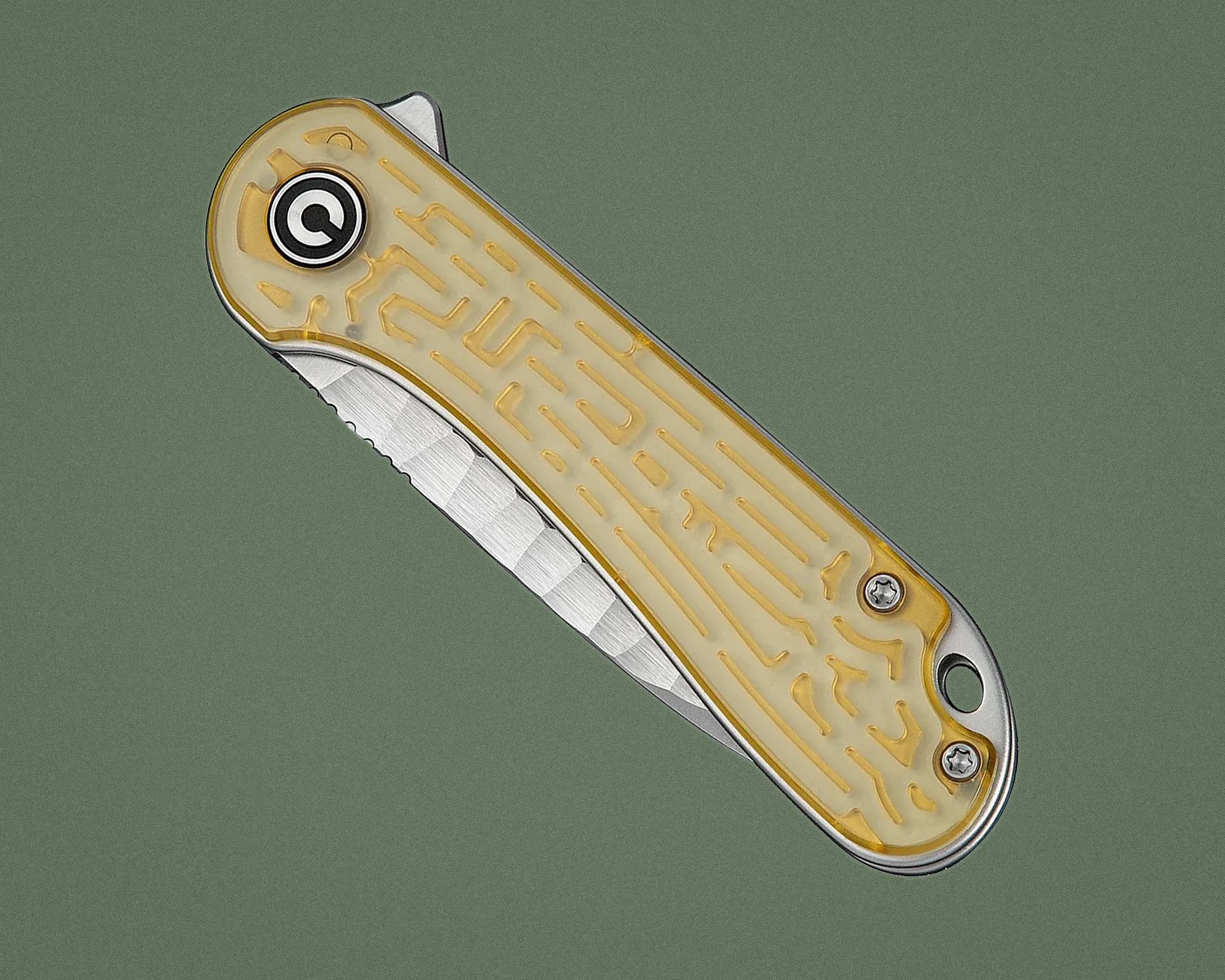 Folding knife with translucent yellow handle and partially serrated stainless steel blade on green background.