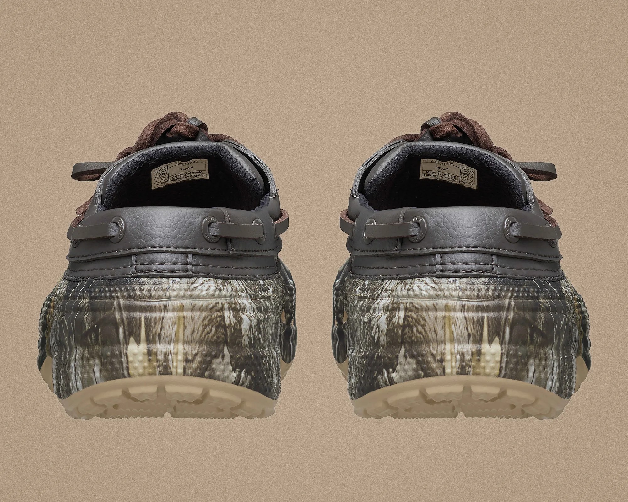 Pair of camo-patterned shoes with dark brown leather trim and beige soles viewed from the back.
