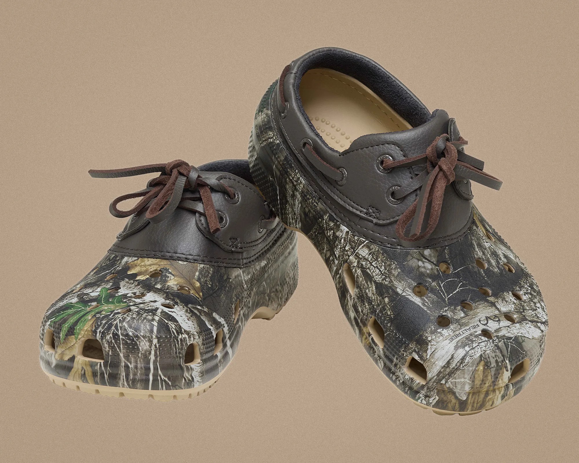 Pair of camouflage-patterned slip-on shoes with dark brown leather trim and laces on a beige background.