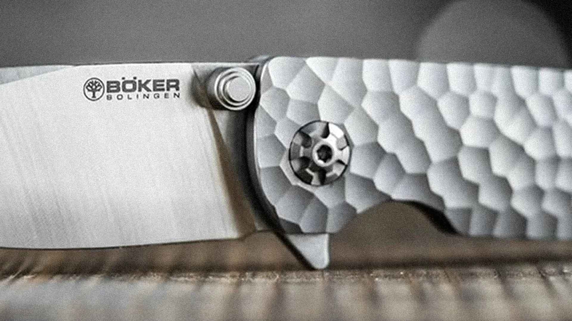 Close-up of a Böker Solingen folding knife blade and textured metal handle with a circular pivot screw.