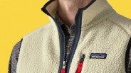 Cream-colored Patagonia fleece vest with black zipper and red pull tabs worn over a brown plaid shirt.