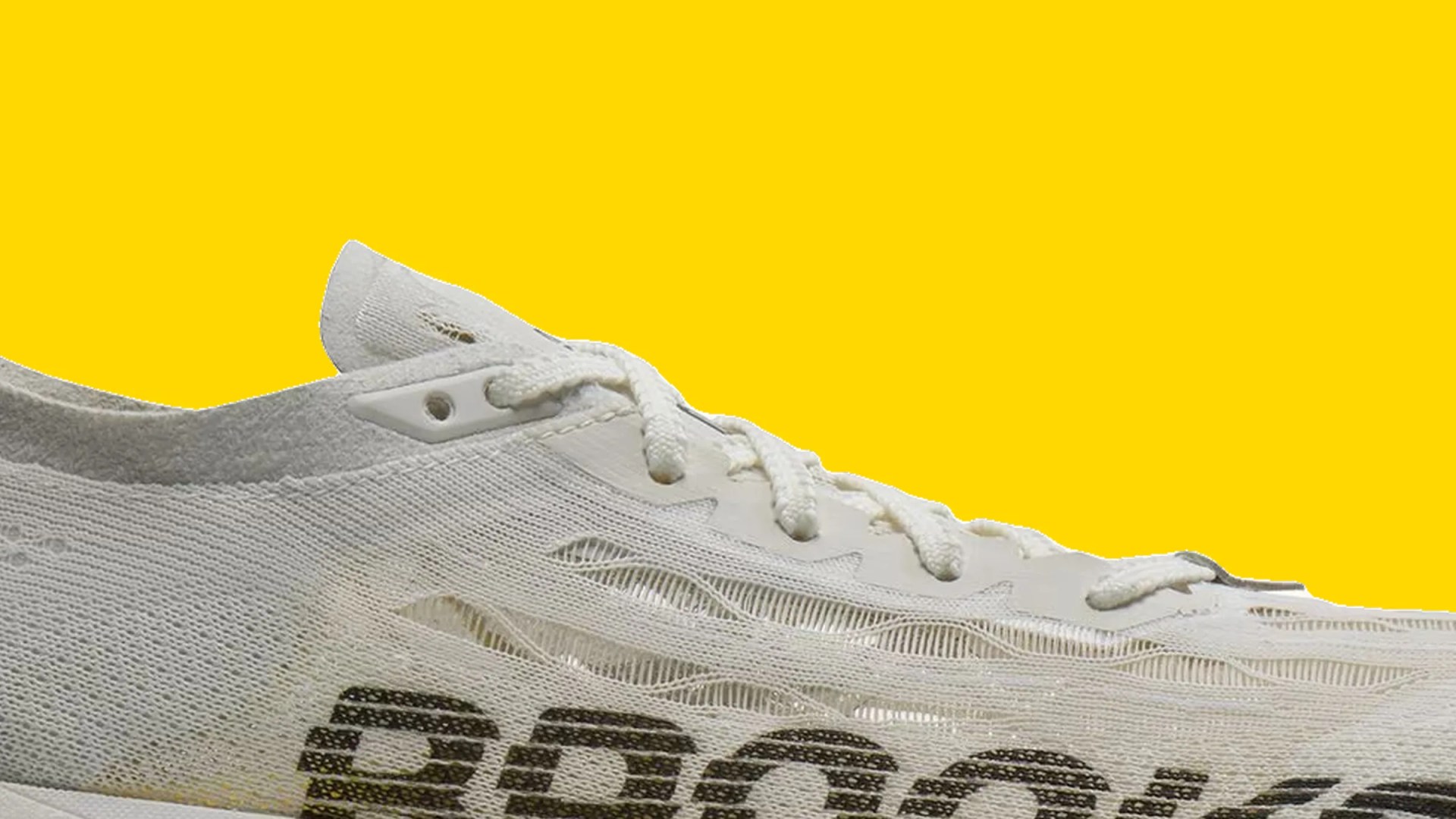 White mesh sneaker with white laces and black text on the side against a yellow background.