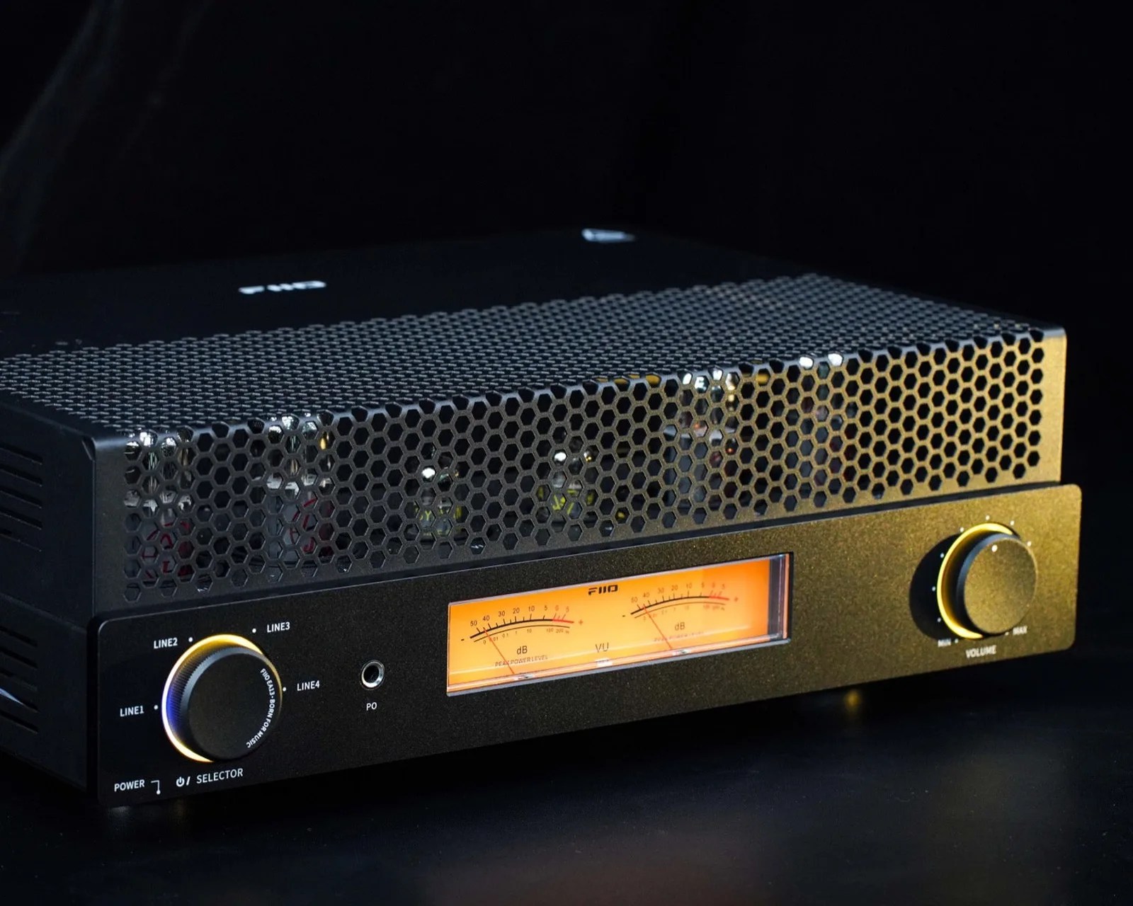 Black FiiO audio amplifier with honeycomb metal grille, analog VU meter, and two large control knobs.