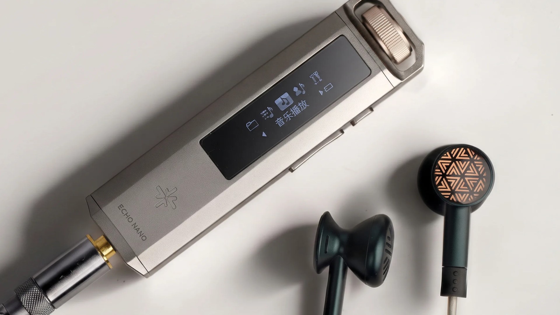 Silver Echo Nano audio device with black wired earbuds featuring a copper geometric pattern on a white surface.