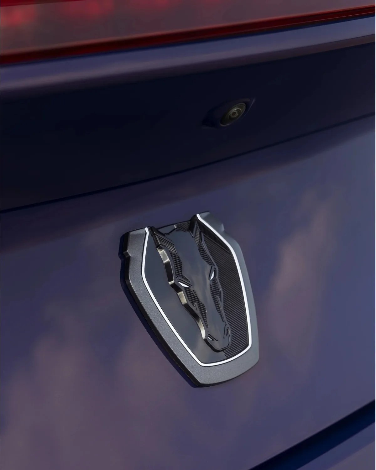 Close-up of a black and silver bull emblem on a dark blue vehicle surface with a rear camera above it.