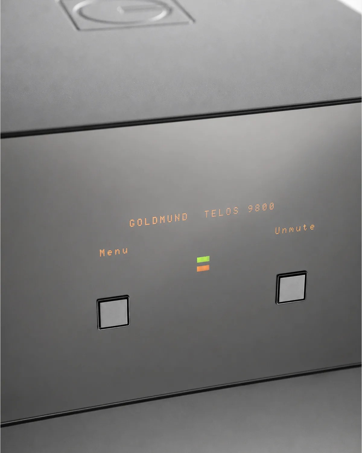 Close-up of a Goldmund Telos 9800 audio device with illuminated menu and unmute buttons on a sleek black panel.