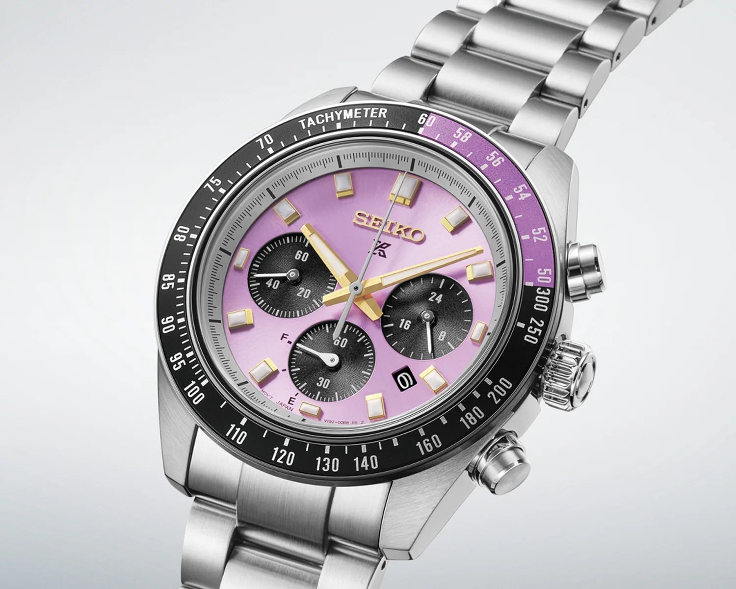 Seiko stainless steel chronograph watch with purple dial, gold-tone hands, and black tachymeter bezel.