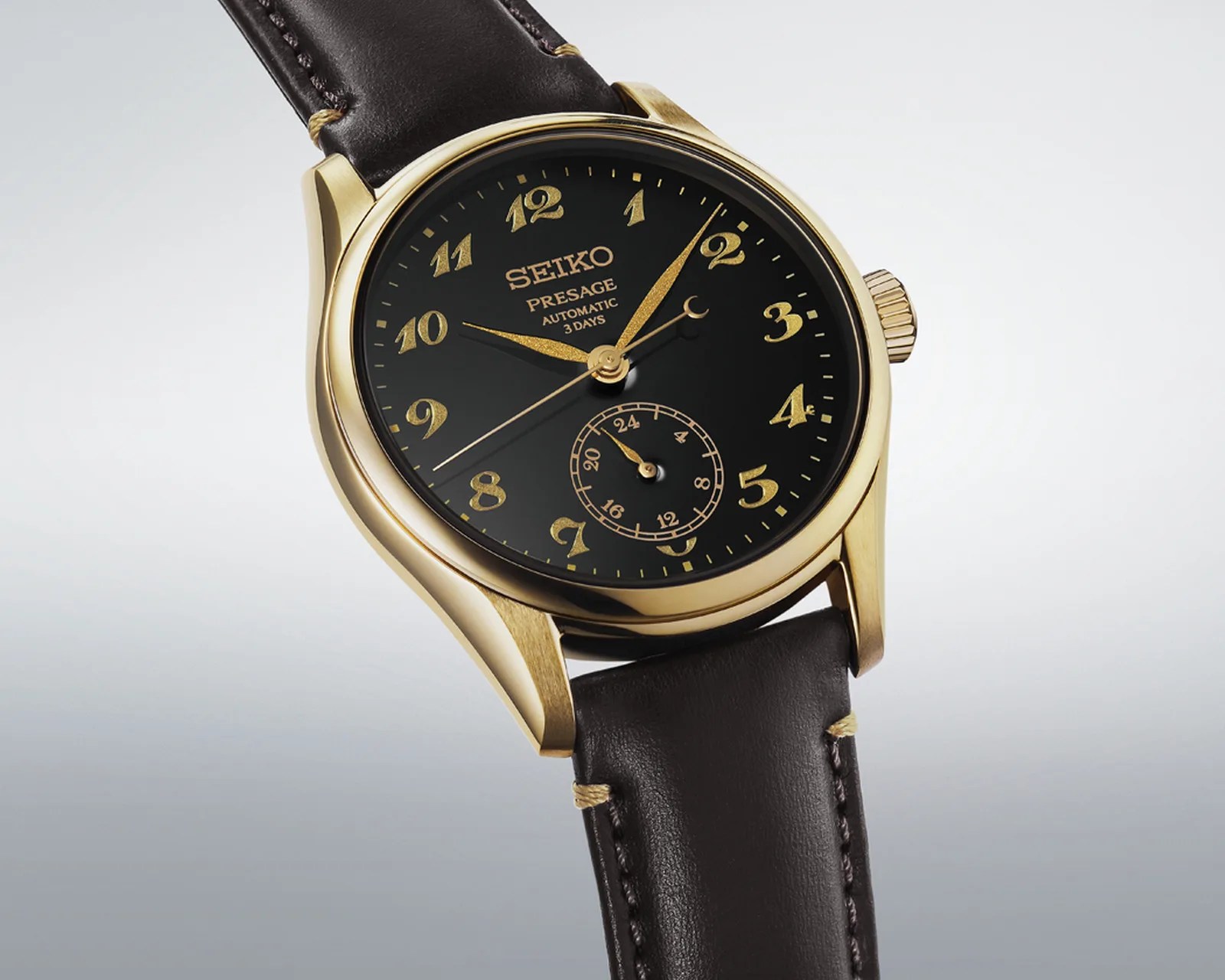 Gold-tone Seiko Presage automatic watch with black dial, gold numerals, and dark brown leather strap.