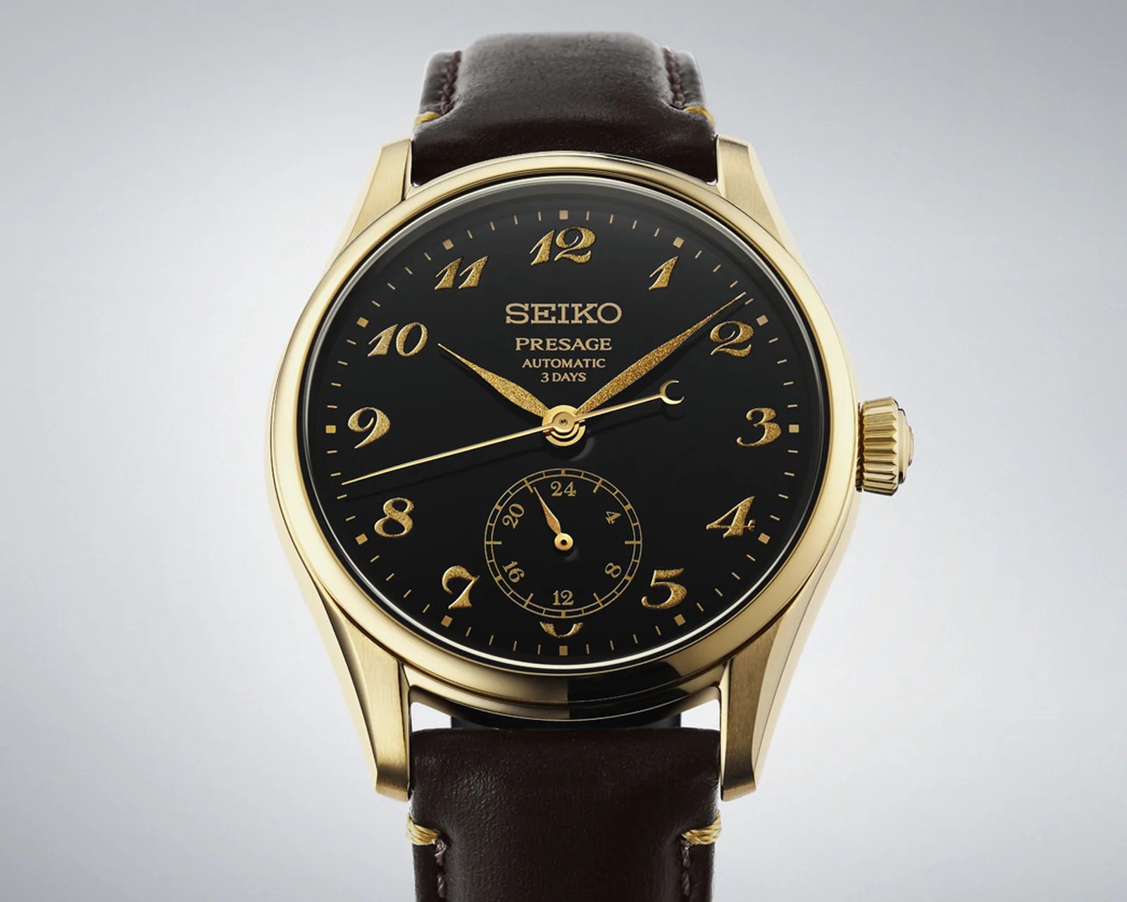 Gold Seiko Presage automatic watch with black dial, gold numerals, and brown leather strap.