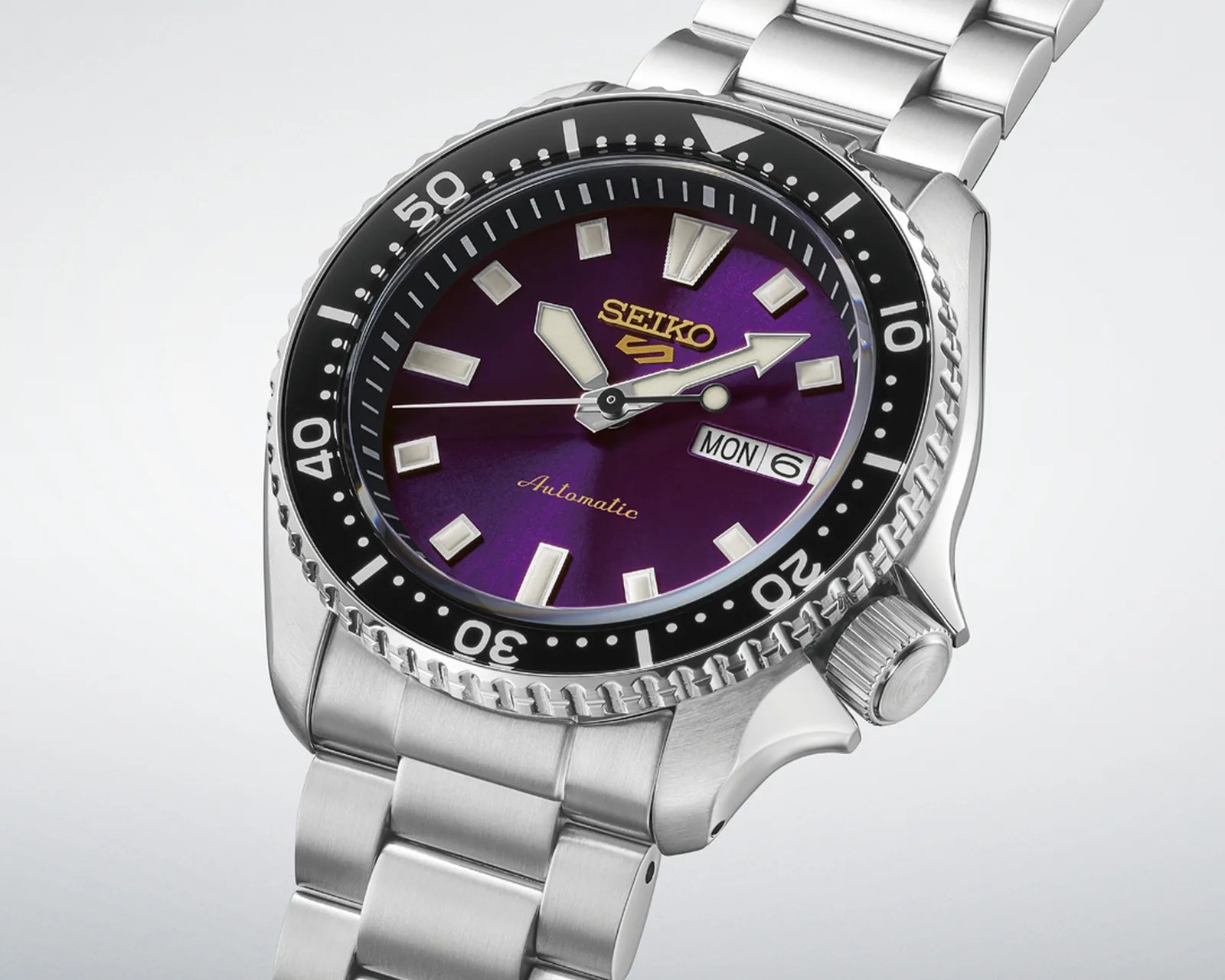 Seiko stainless steel wristwatch with a purple dial, black bezel, and day-date display.