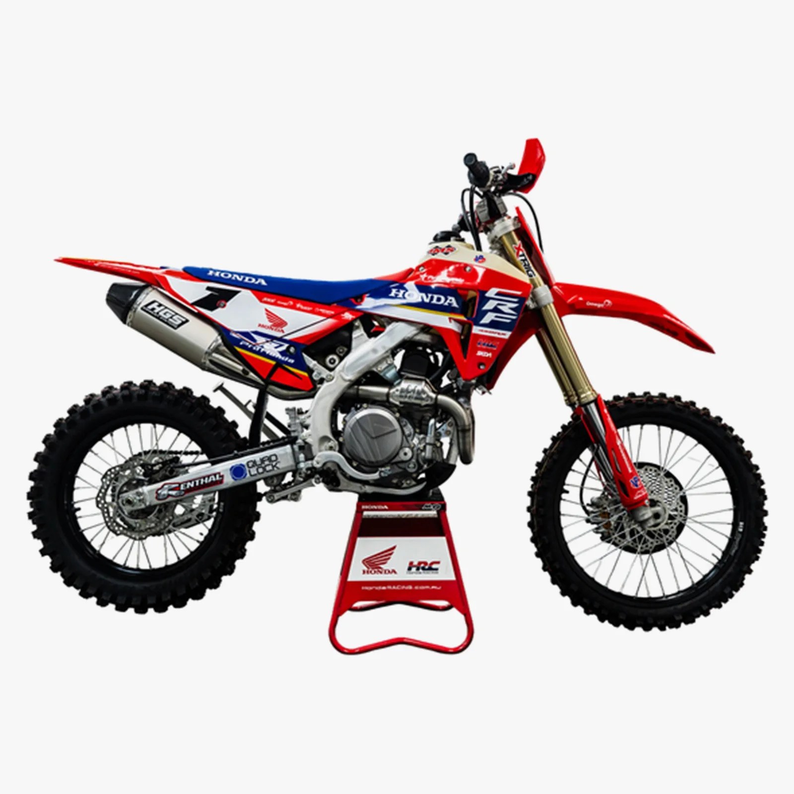 Red, white, and blue Honda CRF dirt bike on a red and white stand with knobby tires.