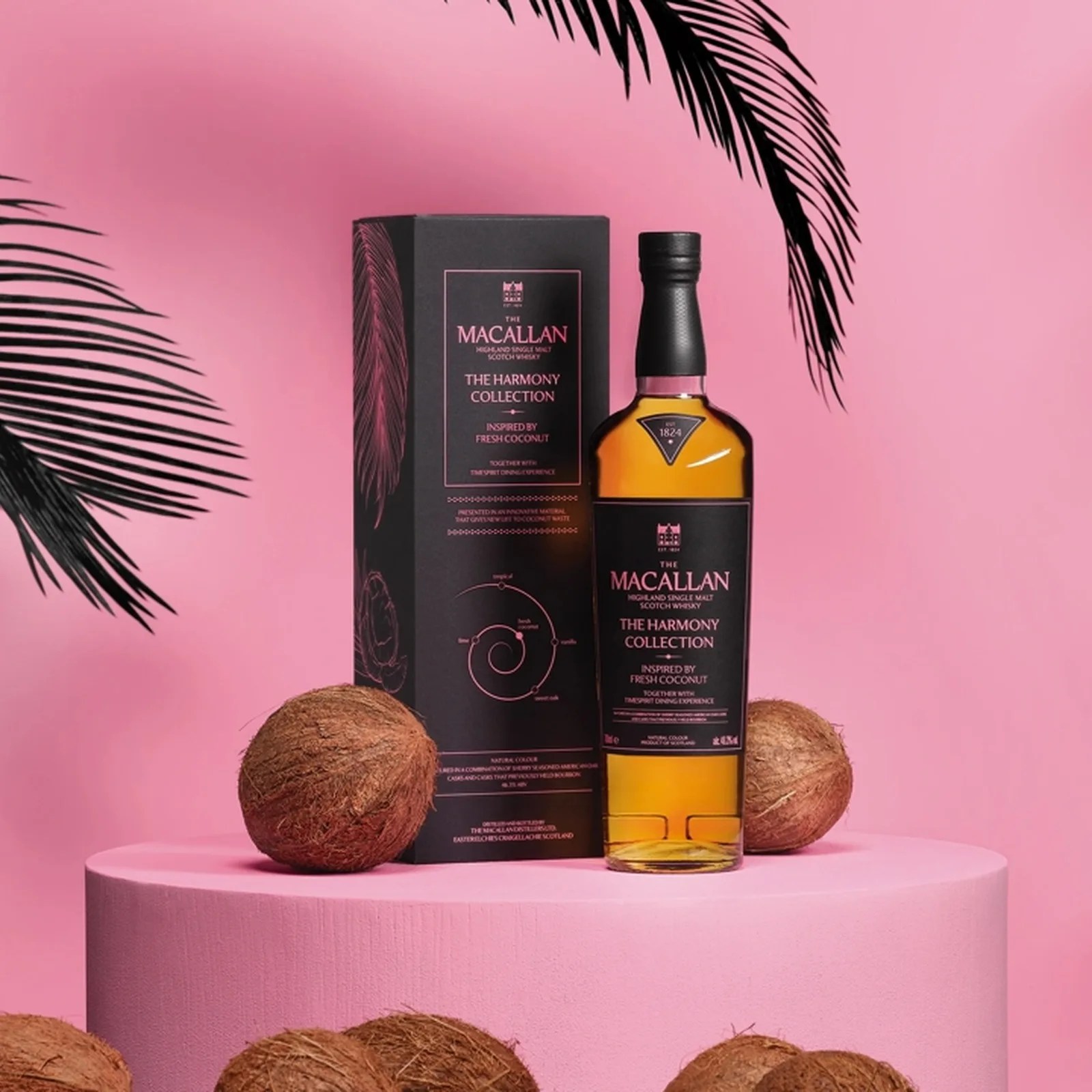 Bottle and box of The Macallan Harmony Collection whisky with coconuts on a pink round pedestal and background.