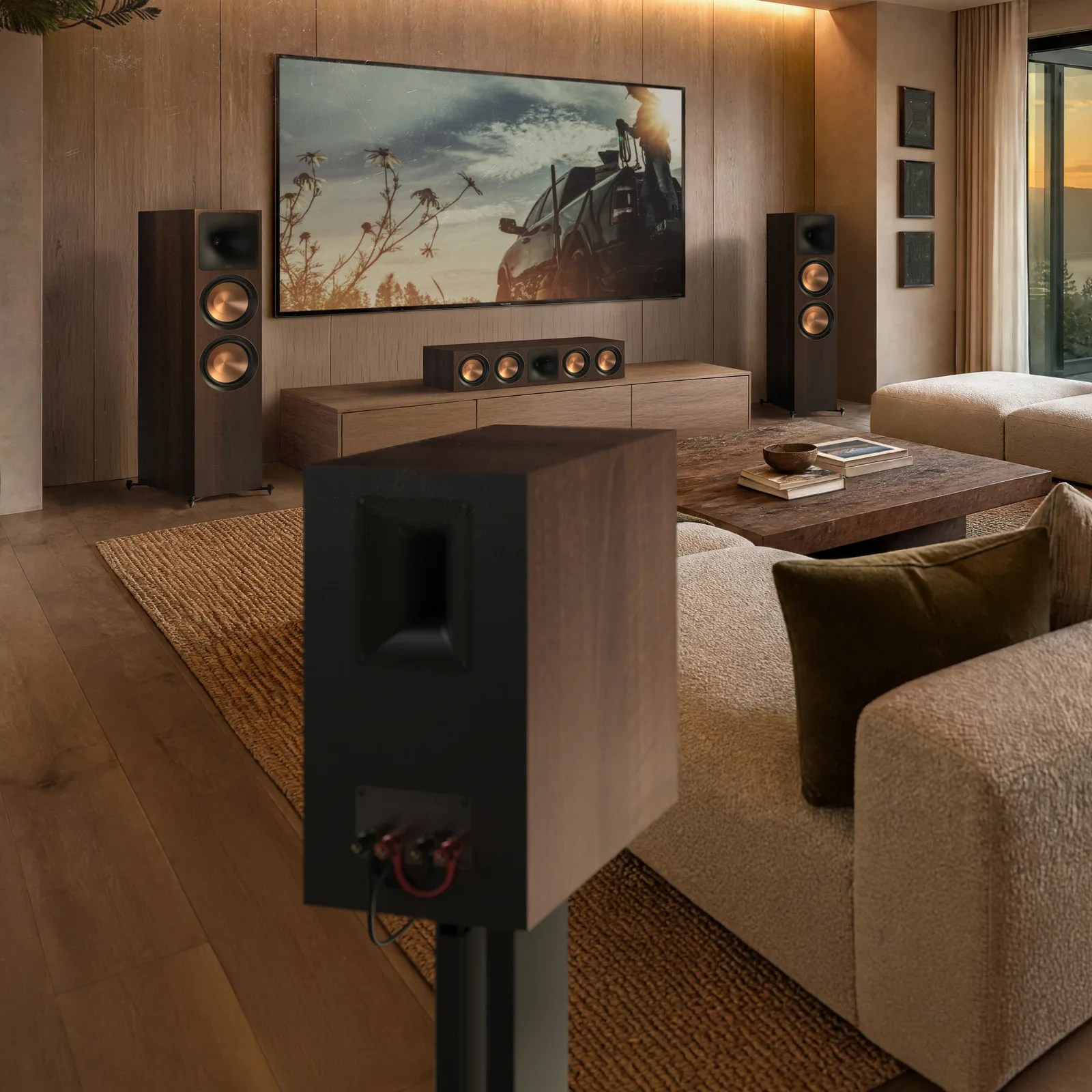 Living room with beige textured sofa, wooden coffee table with books, and a home theater system with black and copper speakers.