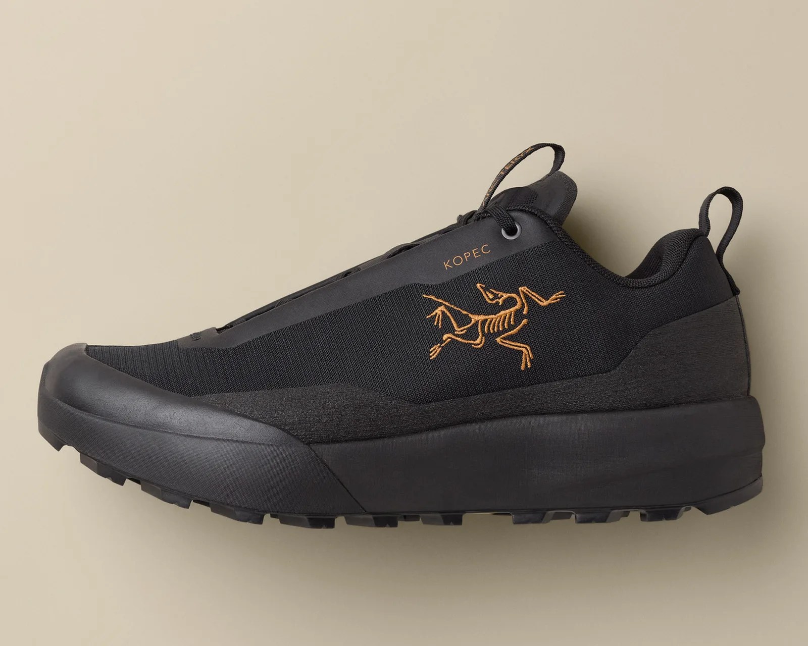Black low-top sneaker with orange skeletal lizard logo and "KOPEC" text on the side.