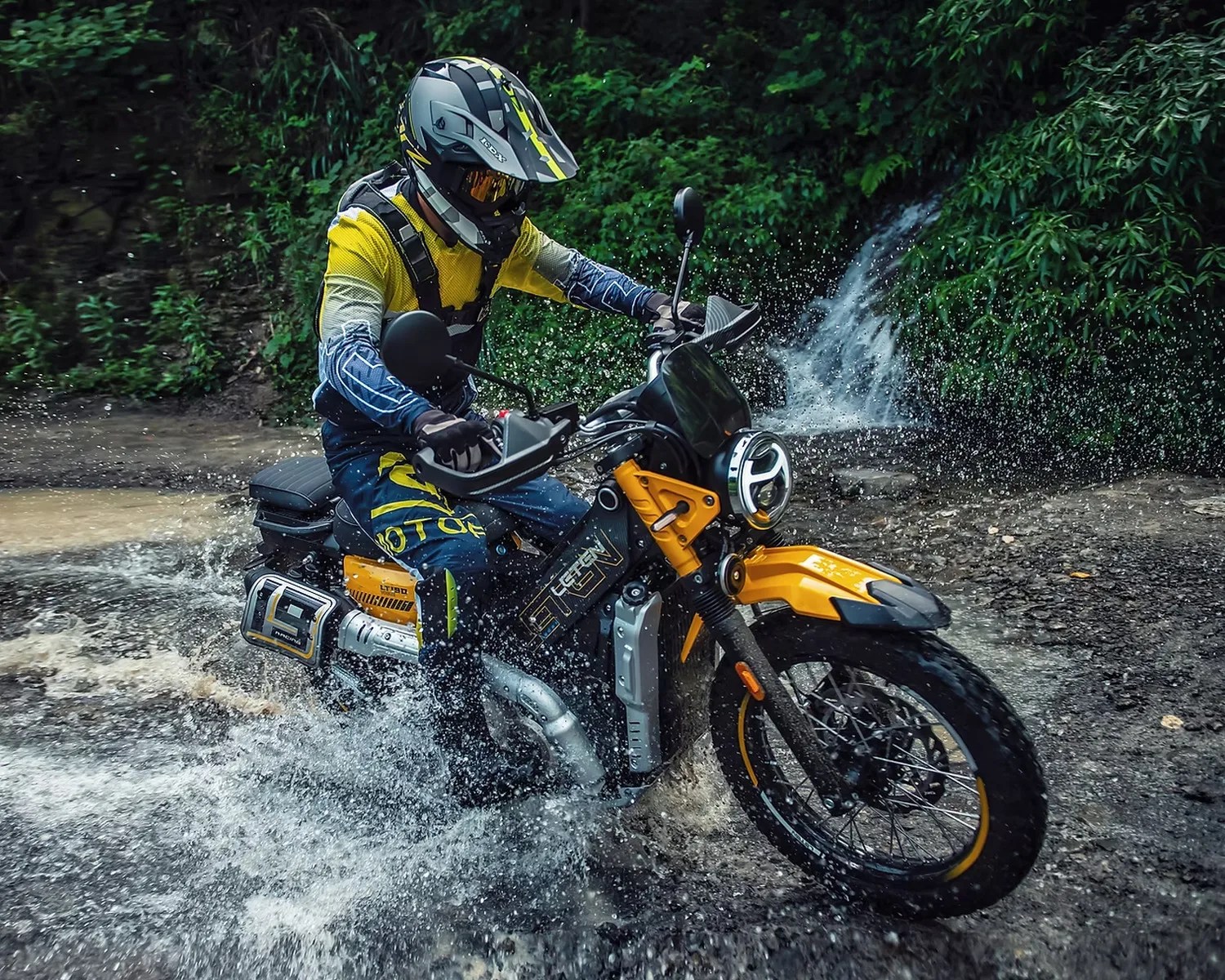 Yellow and black off-road motorcycle splashing through shallow water with rider in protective gear.