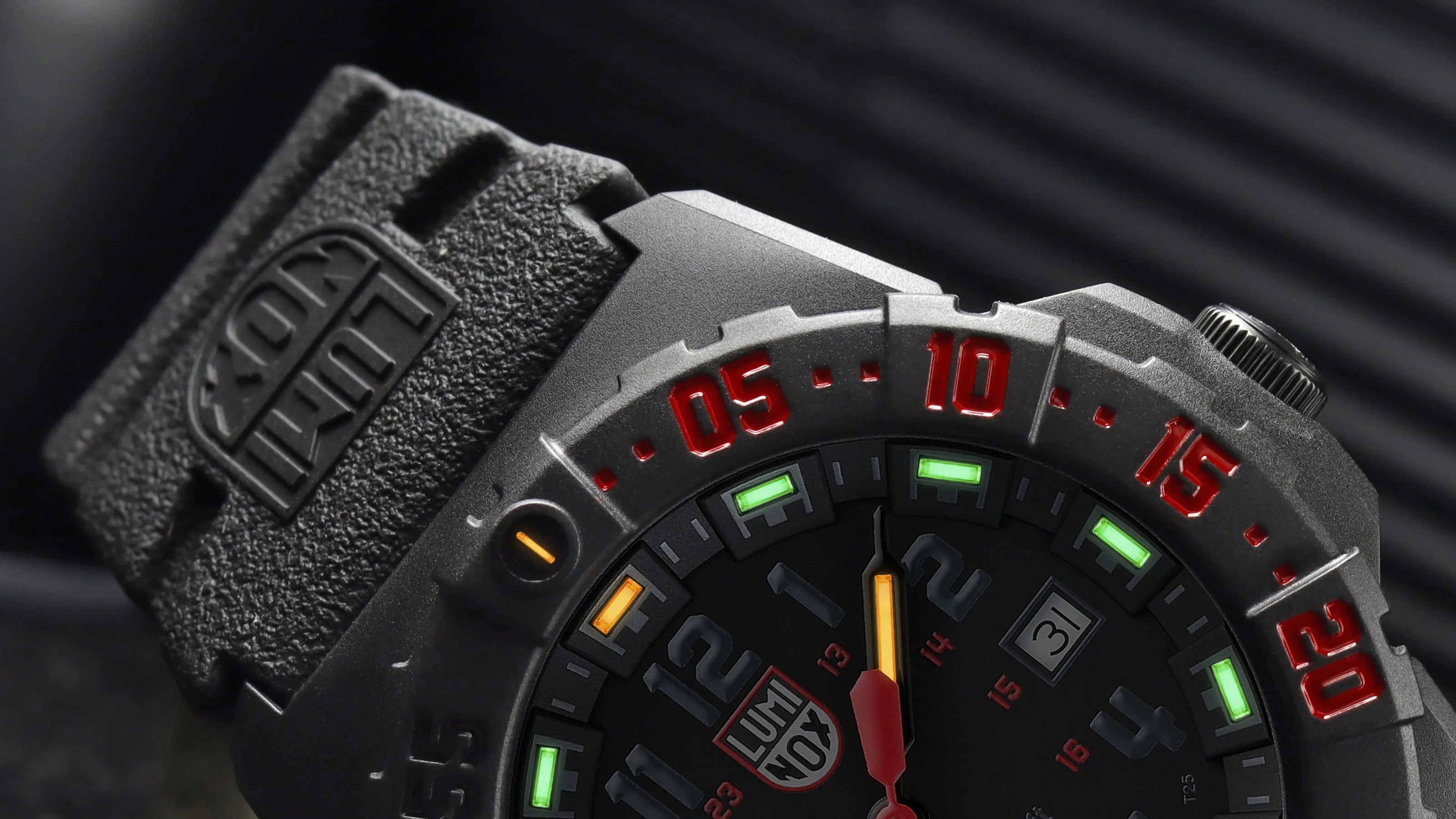 Close-up of a black Luminox watch with red numbers on the bezel and green and orange luminescent markers on the dial.