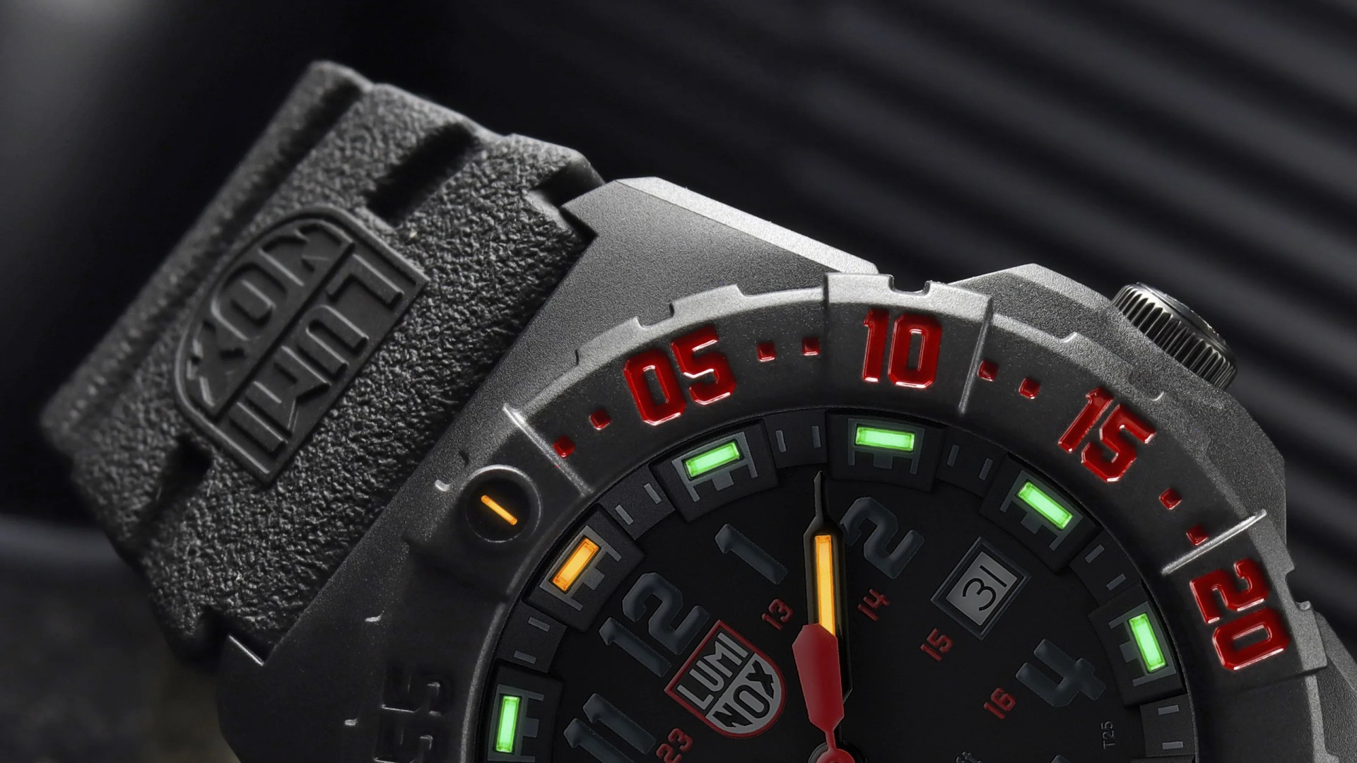 Close-up of a black Luminox watch with red numbers on the bezel and green and orange luminescent markers on the dial.
