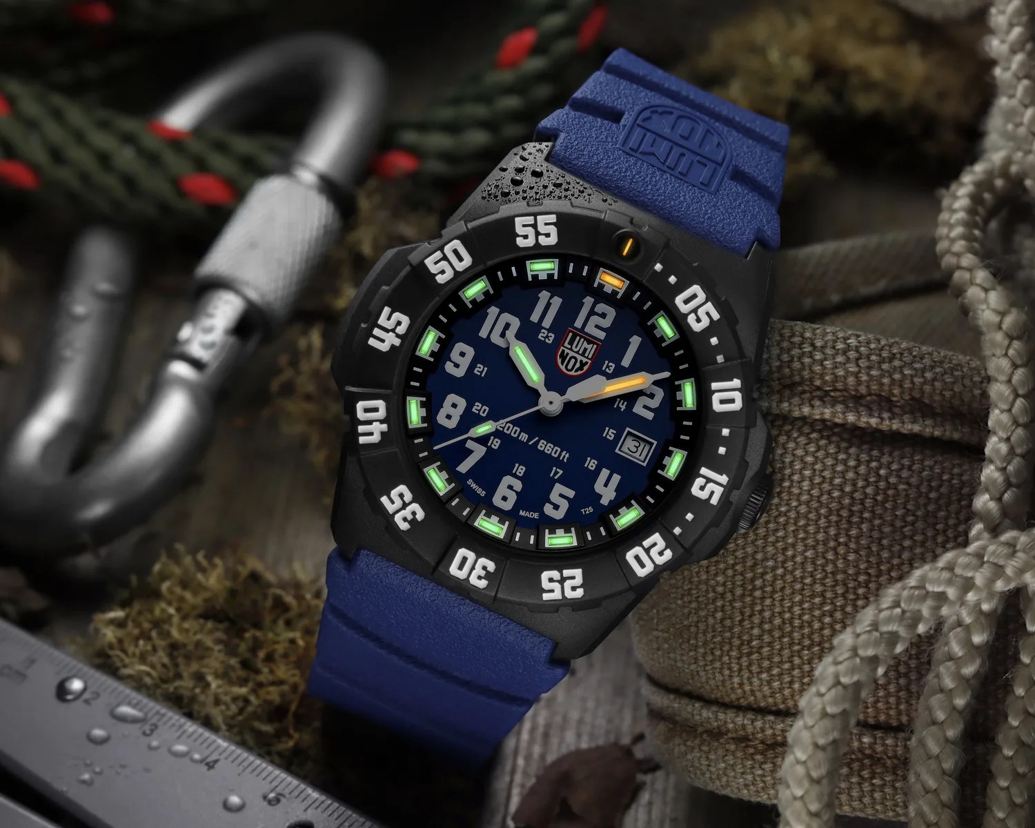 Black Luminox watch with blue dial and strap, luminous green and orange hands, and white numeric bezel.