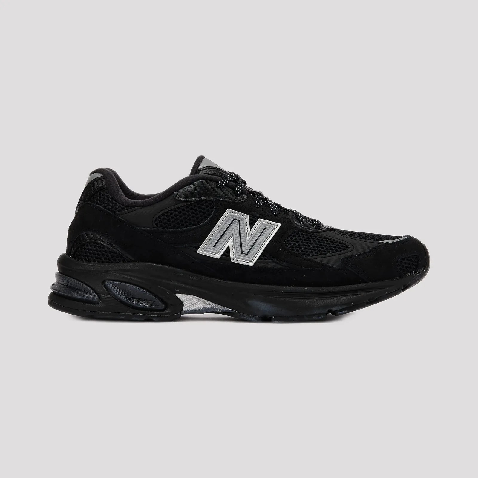 Black New Balance sneaker with mesh and suede upper and reflective silver "N" logo on the side.
