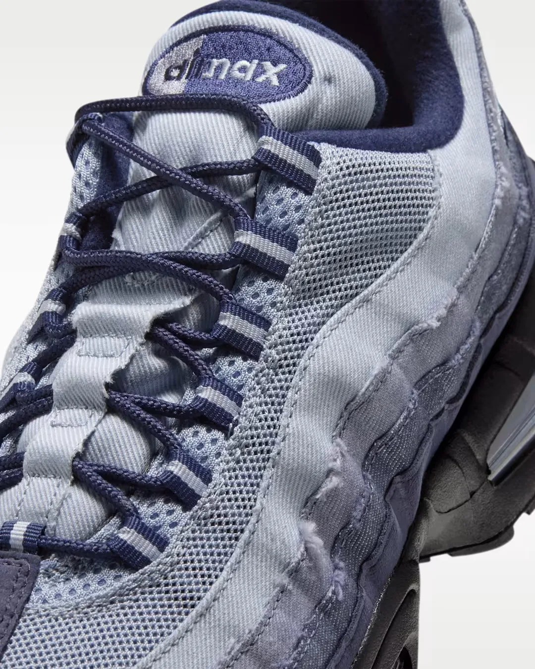 Close-up of a light blue and navy Nike Air Max sneaker with mesh and fabric upper and navy laces.