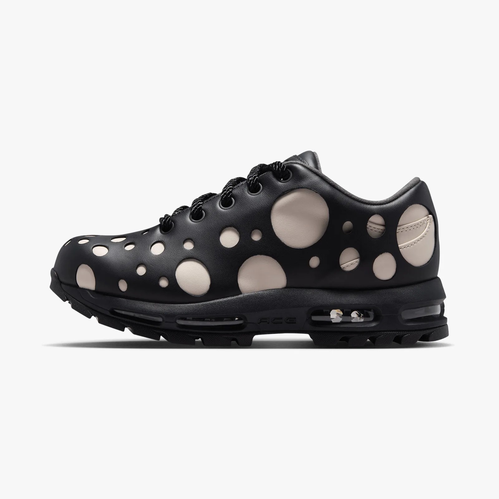 Black sneaker with large beige circular cutouts and visible air cushioning in the sole.