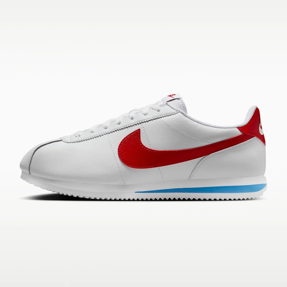 White Nike Cortez sneaker with red swoosh and heel tab, blue accent on sole, and white laces.