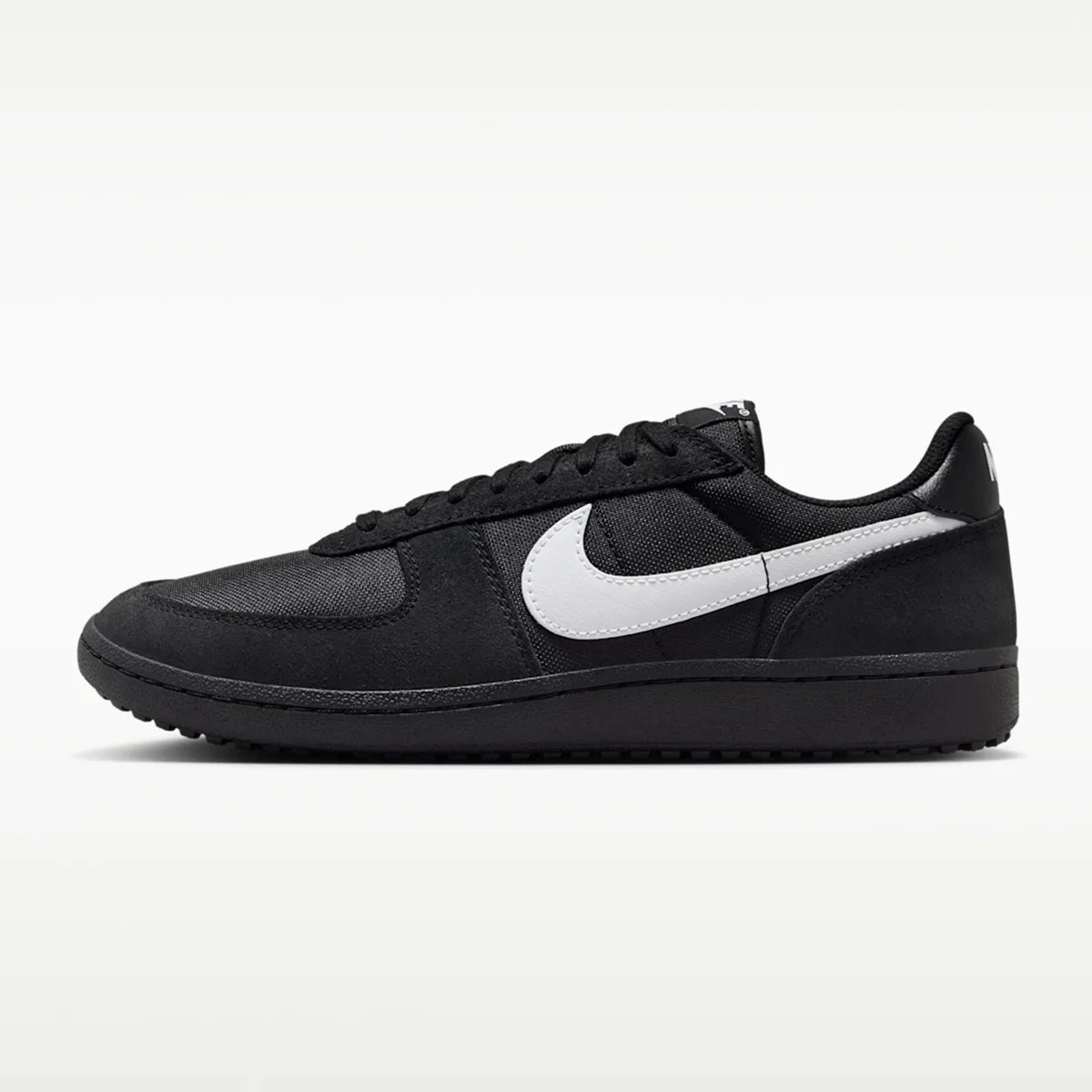 Black low-top Nike sneaker with white swoosh logo and black sole, shown in side profile.