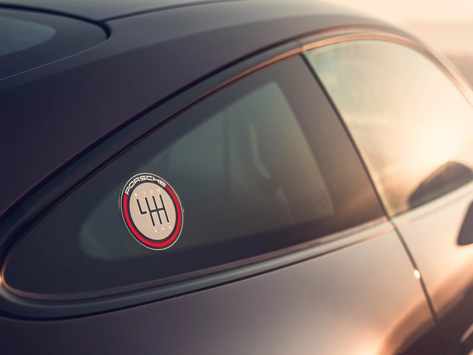 Round Porsche decal with a manual gear shift pattern on a dark car window.