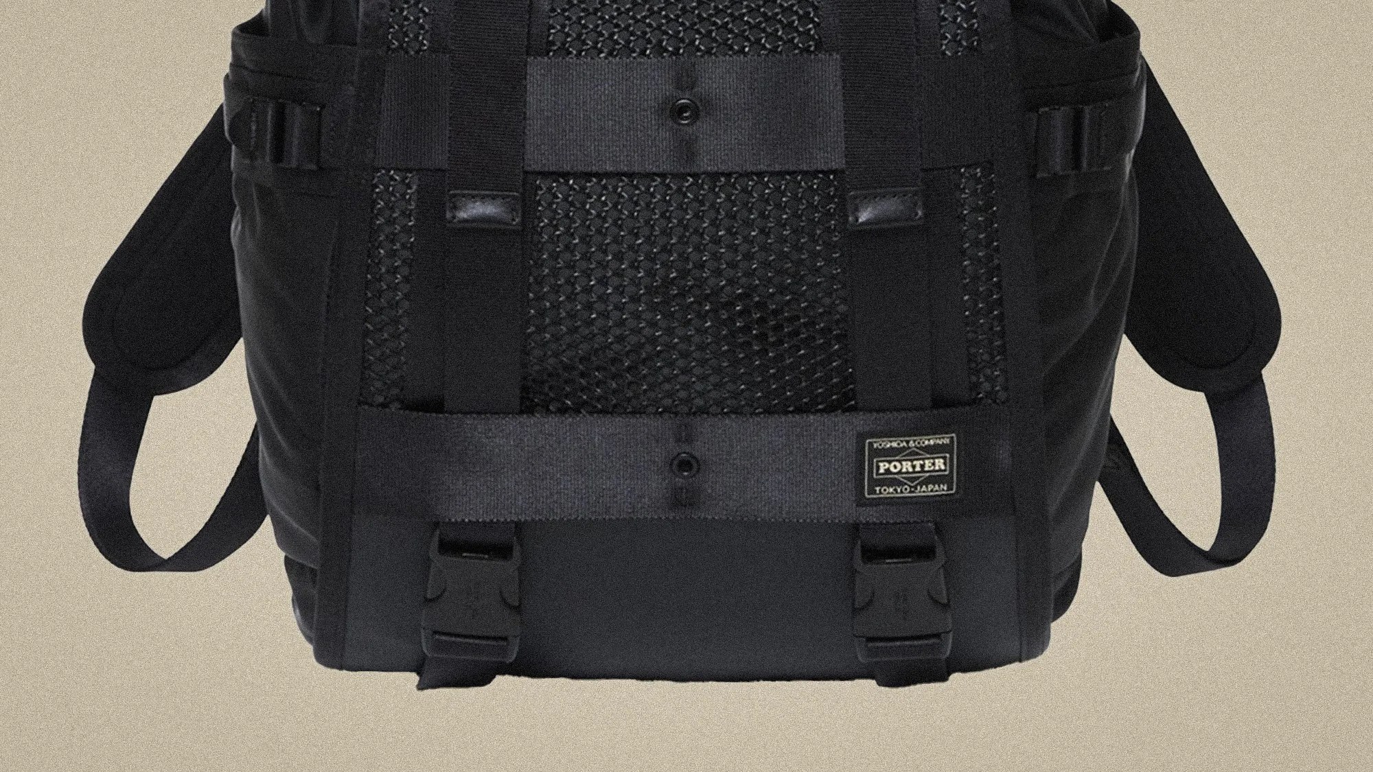 Black Porter backpack with mesh panel, adjustable straps, and front buckle closures on a beige background.