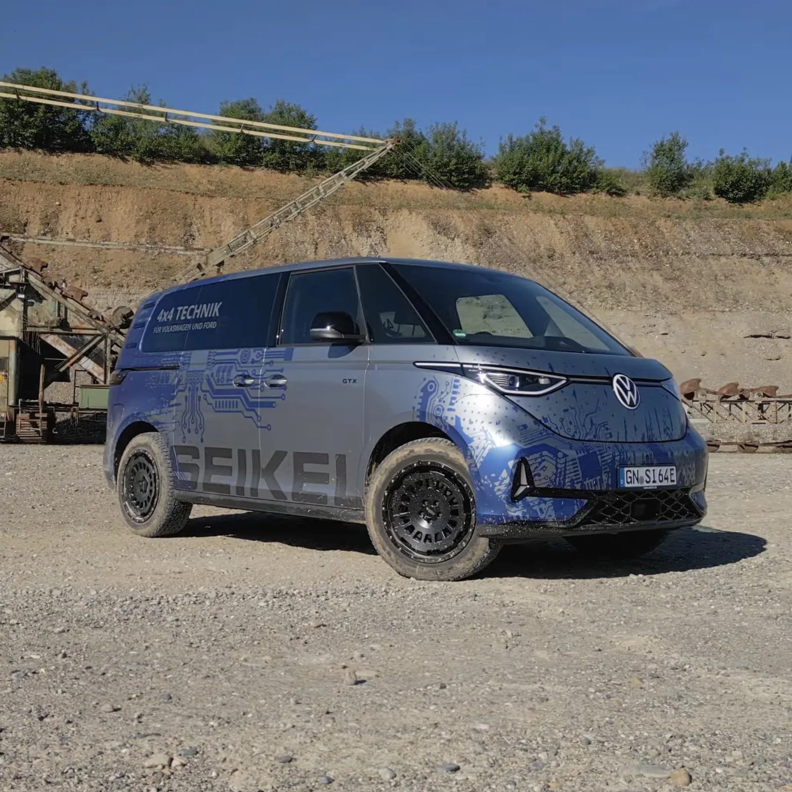 Blue and gray Volkswagen electric van with Seikel branding parked on gravel near a dirt embankment.