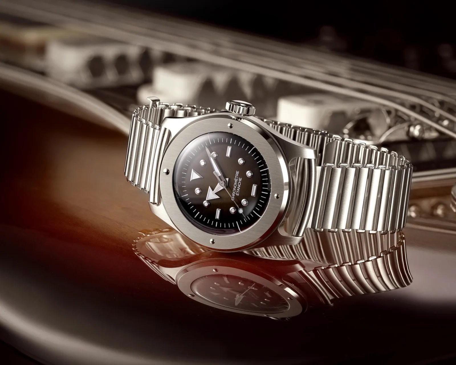 Silver metal wristwatch with black dial and geometric hour markers resting on a wooden surface.