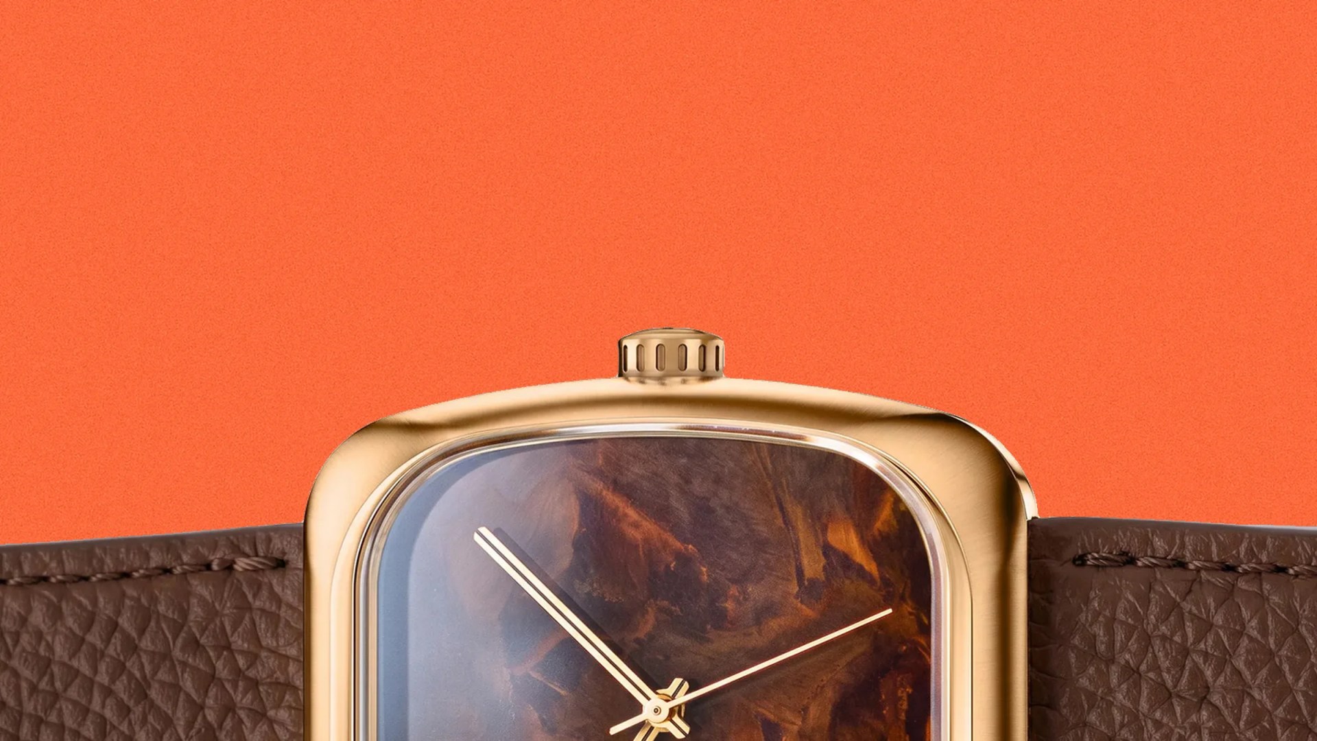 Close-up of a gold watch case with a brown marbled dial and a textured brown leather strap against an orange background.