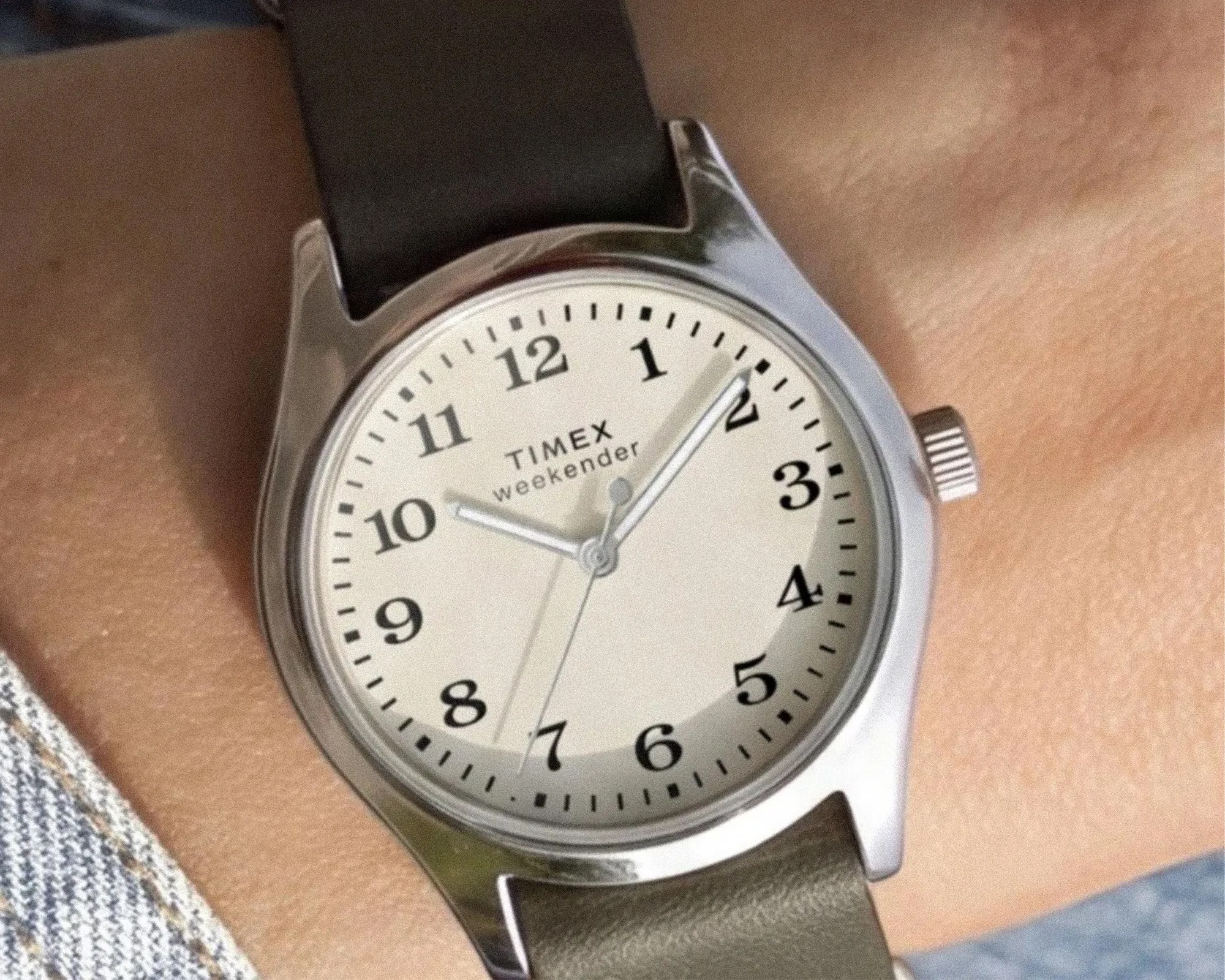 Silver Timex Weekender watch with white dial and black leather strap on wrist.