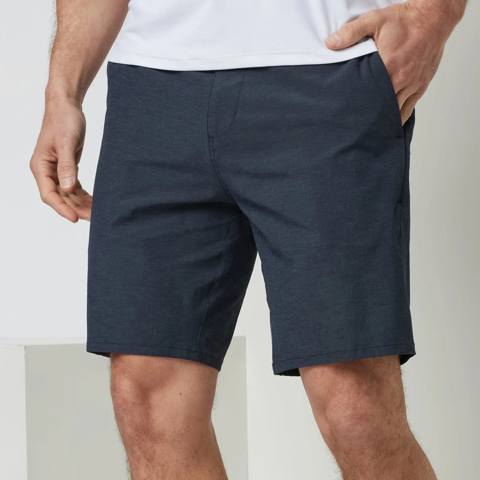 Navy blue casual shorts worn by a person with one hand in pocket.