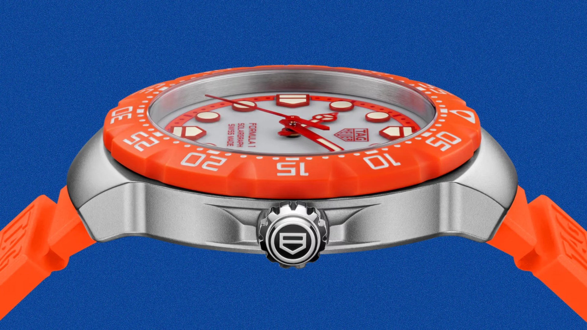 Silver TAG Heuer Formula 1 watch with orange bezel and strap on blue background.