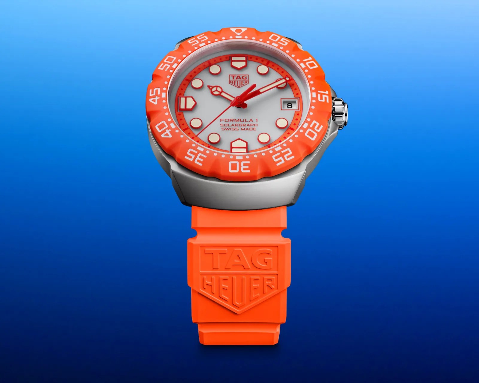 TAG Heuer Formula 1 watch with orange bezel and strap, white dial, and date display on blue background.